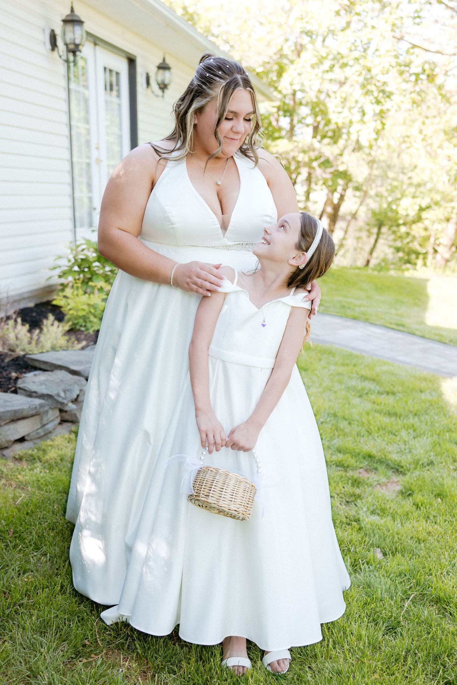 Wedding portraits taken outside a white building showing elegant poses in white dresses.