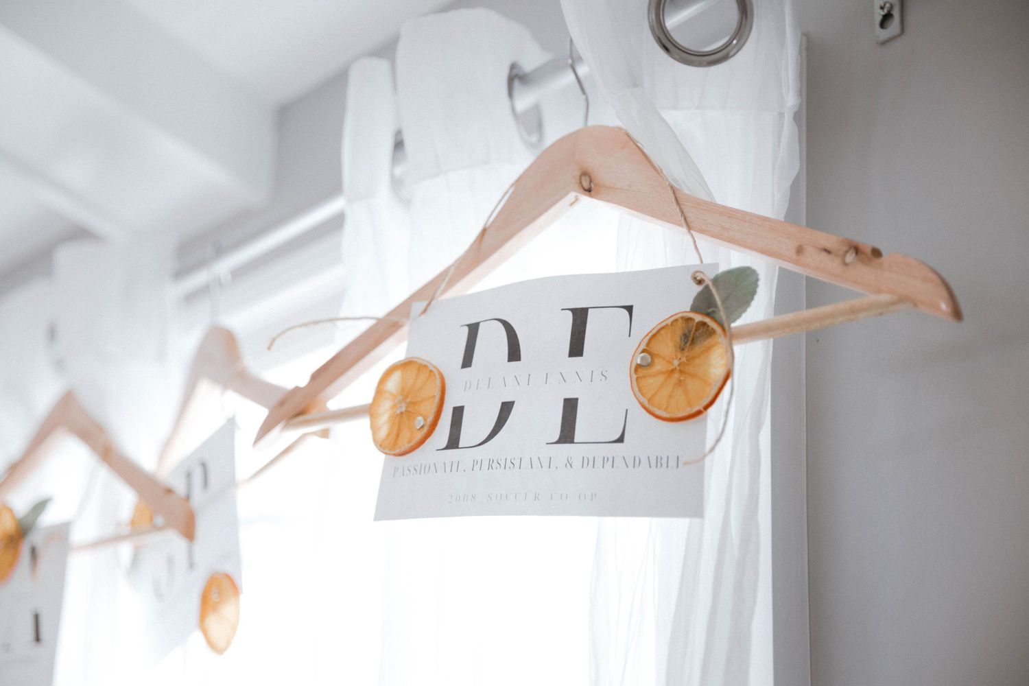 Wooden hangers displaying gold letter wall decor elements against a white wall in repetitive sequence.