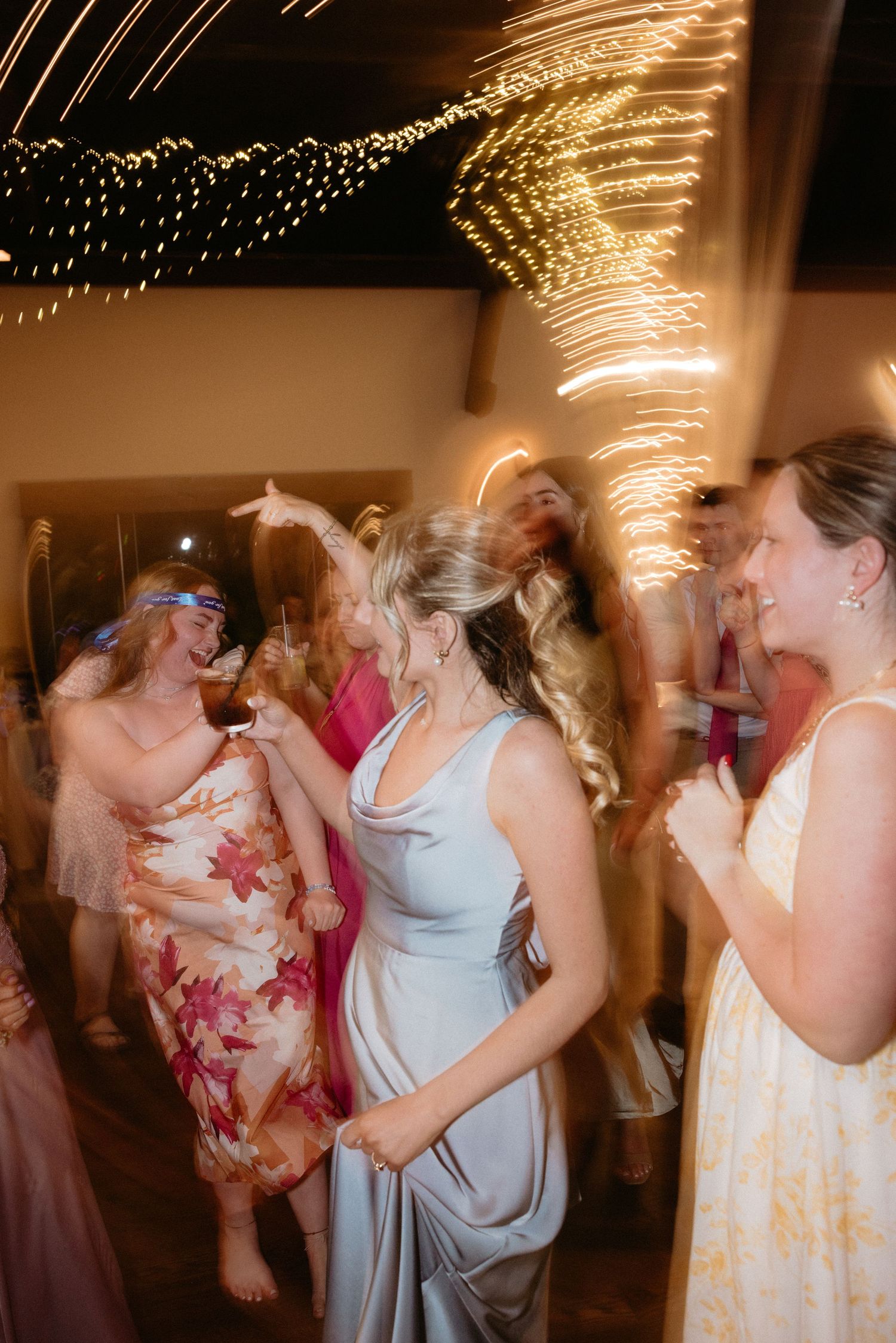 Blurred motion dance photos from a wedding reception with string lights creating a dreamy atmosphere.