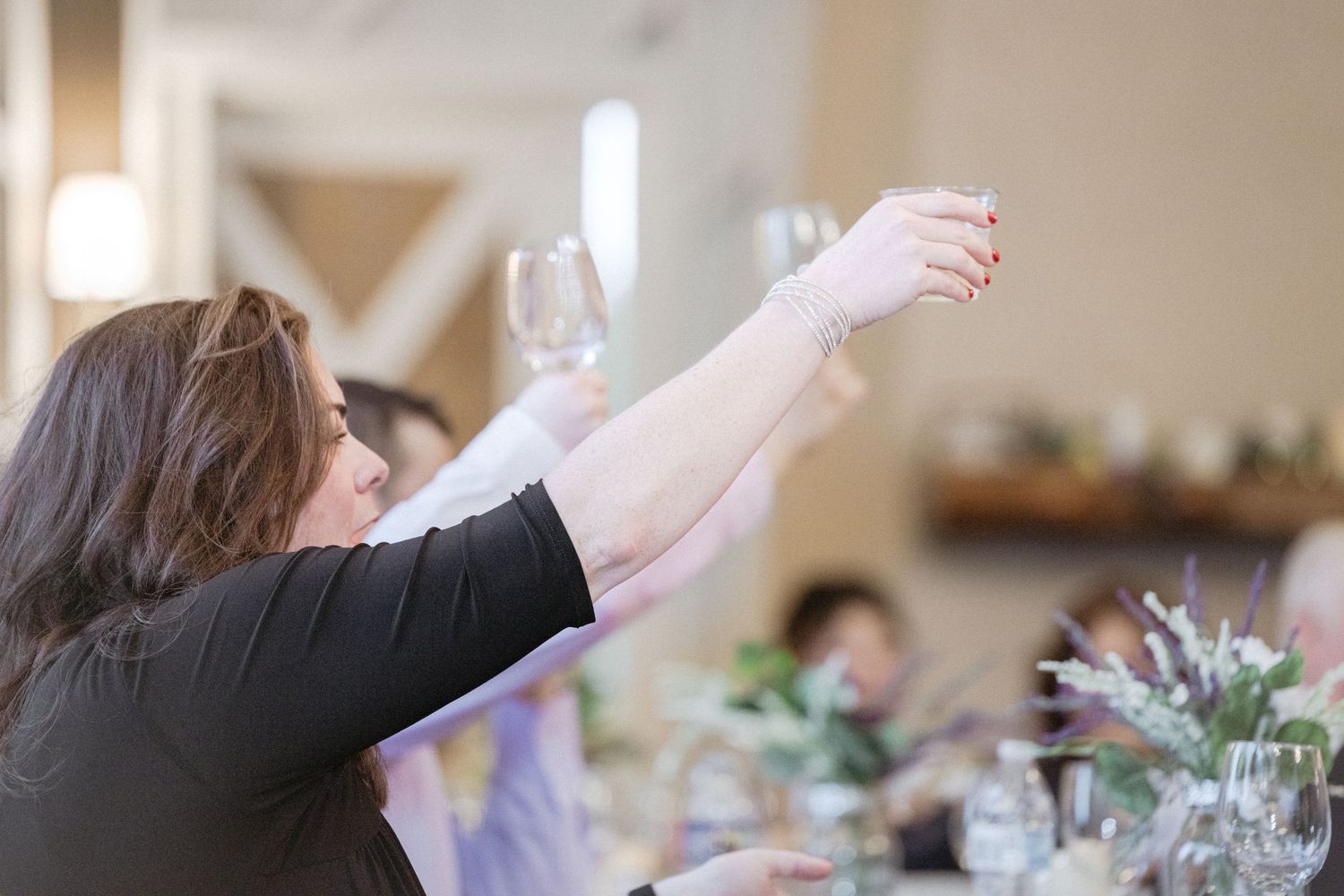Wedding guests with raised glasses participate in a celebratory toast during a reception.