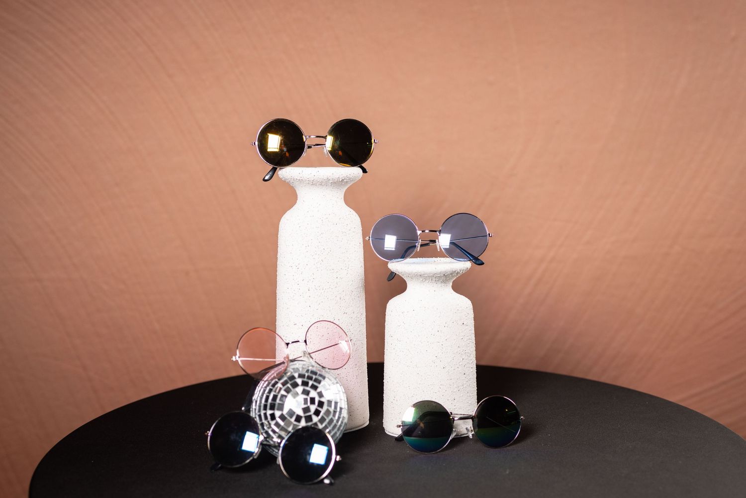 Mickey Mouse ears and sunglasses arranged with white cylindrical objects and disco ball.