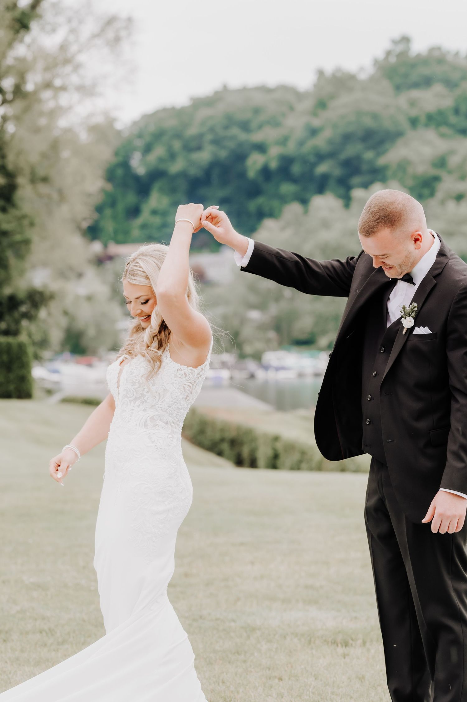 A couple shares a romantic dance moment outdoors on their wedding day, with the bride in white and groom in black tuxedo.