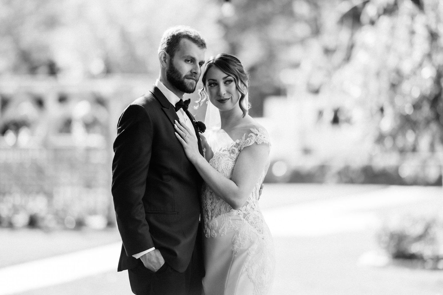 A romantic black and white wedding photo series showing tender moments between the newlyweds in an outdoor setting.