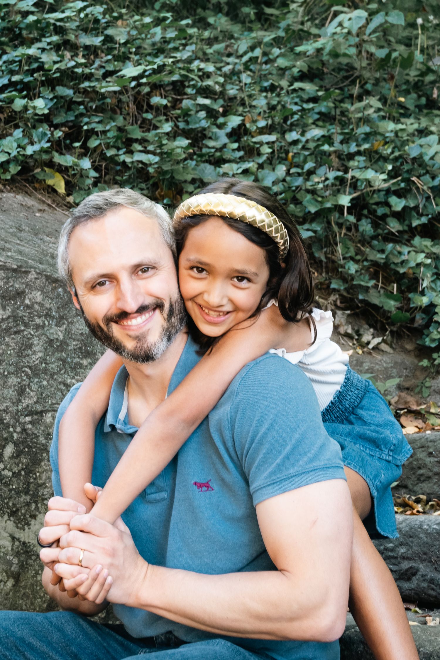 A couple shares tender moments while relaxing outdoors against a backdrop of green foliage.