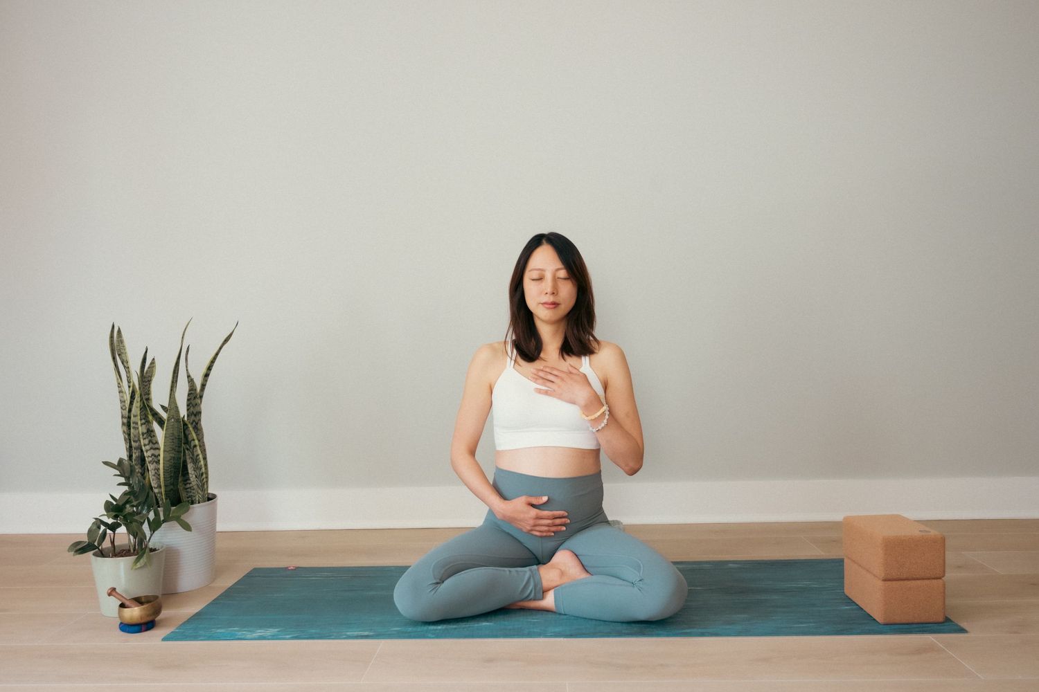 A yoga or meditation session on a blue mat with props and plants in a minimalist setting.