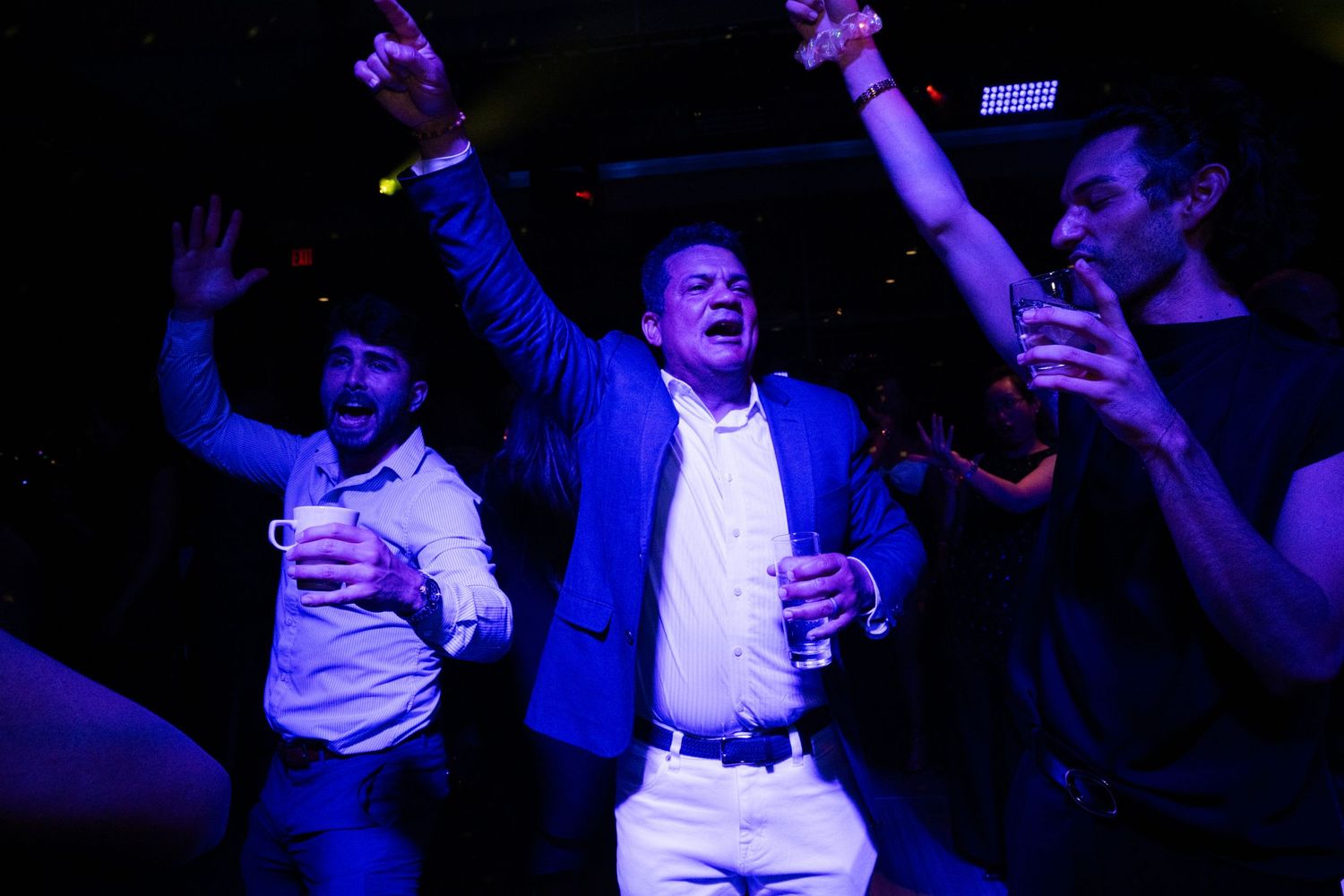 Three men celebrating and dancing energetically at a nightclub party event.