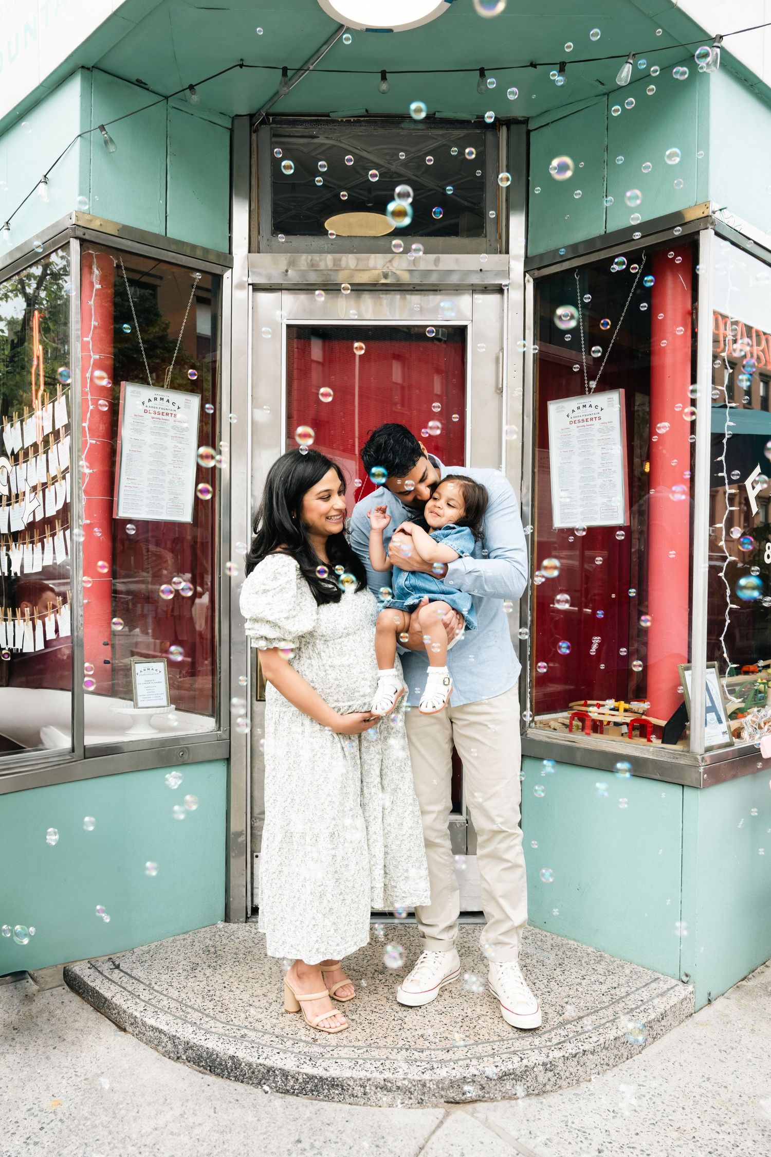 Family standing in front of a storefront with bubbles floating around them.