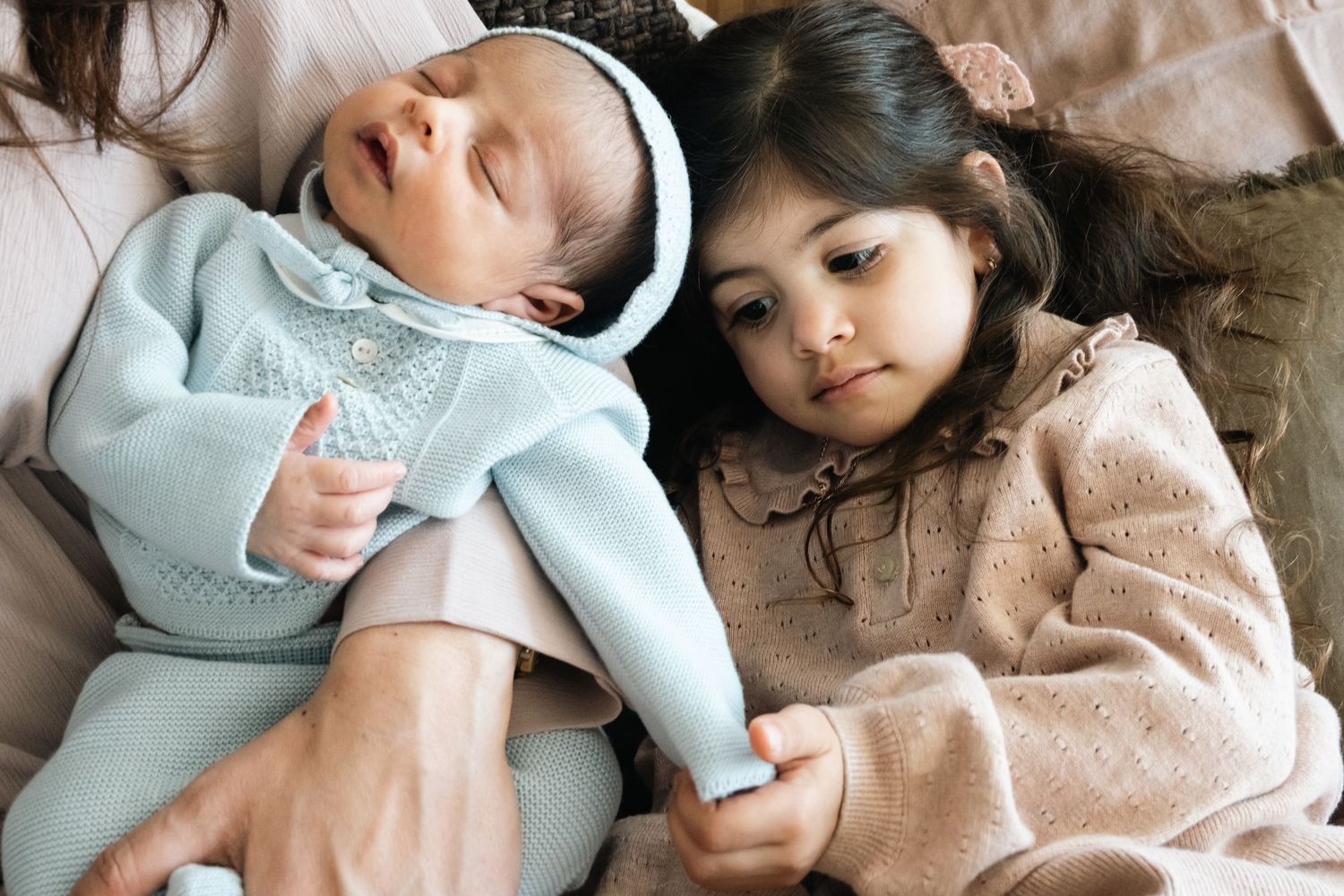 Intimate newborn lifestyle photography session showing tender moments between parent and baby on bed.