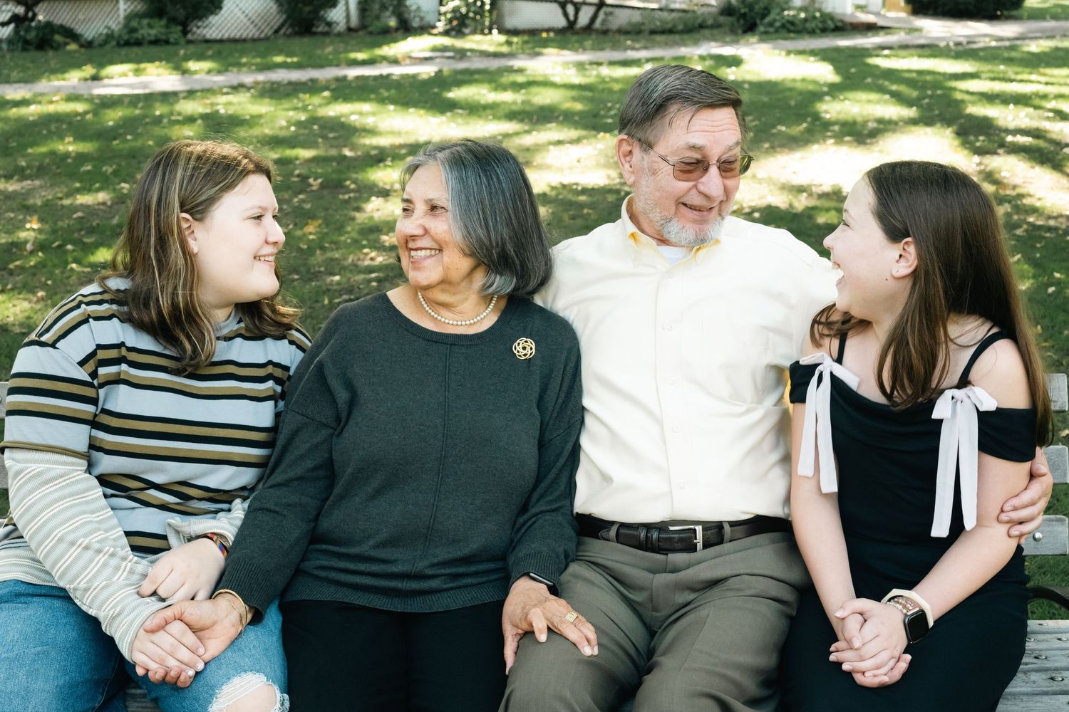 Multi-generational family sharing joyful moments together on outdoor benches.