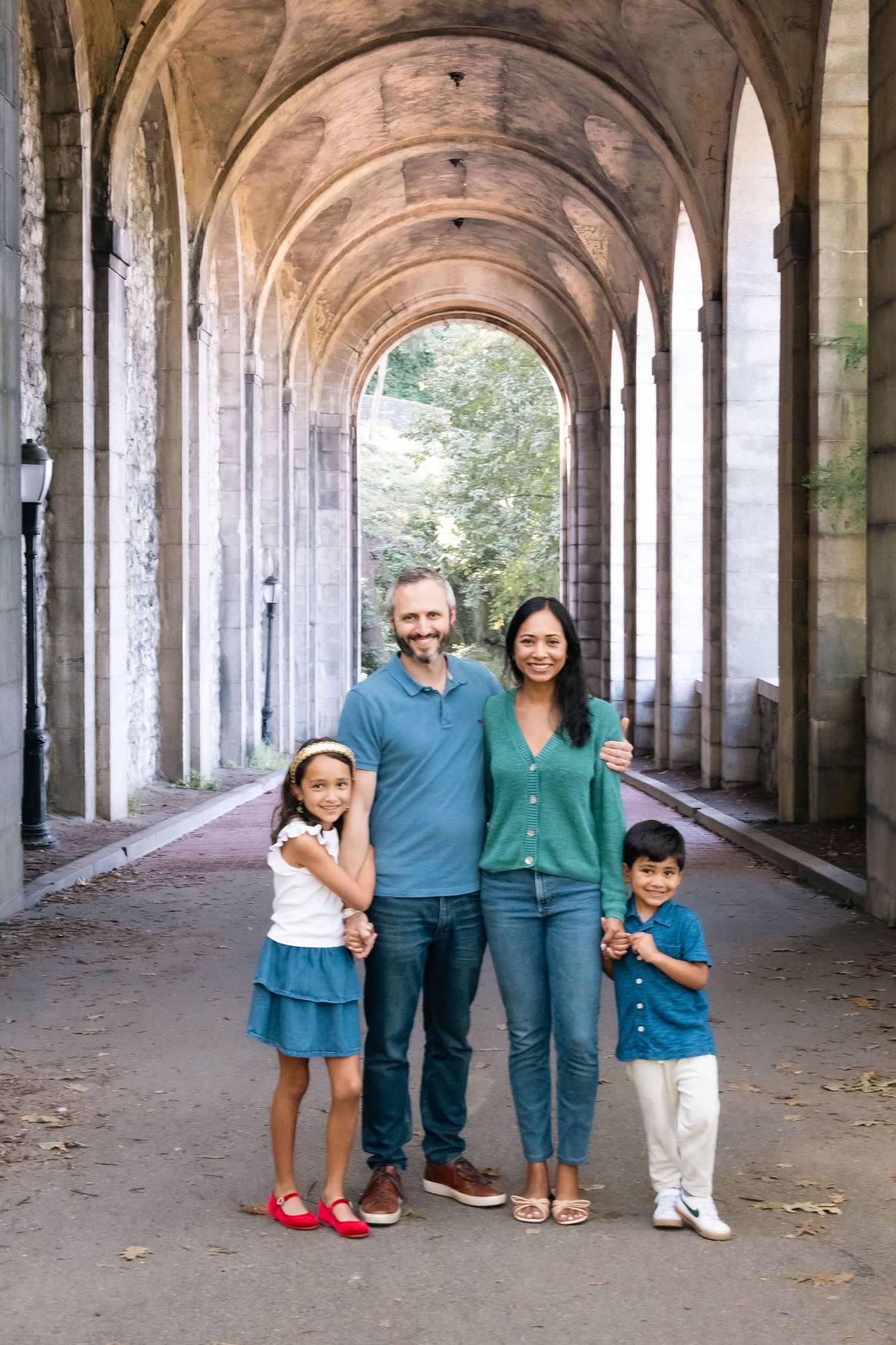 A family poses for photos under a beautiful arched colonnade with repeating architectural columns.