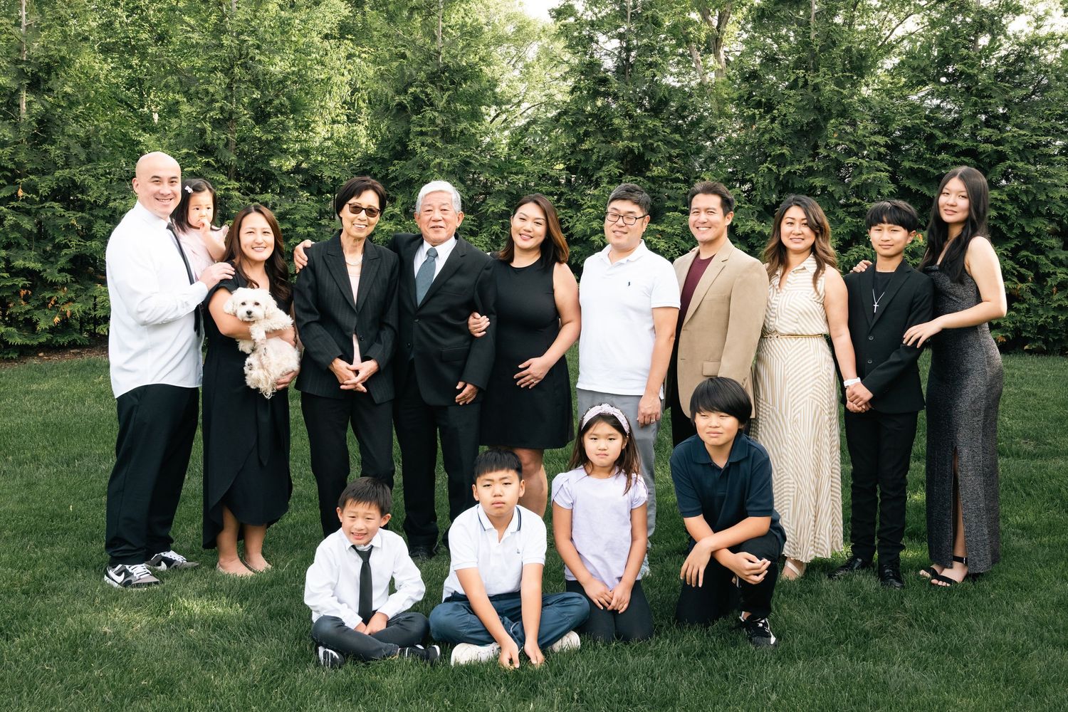 Large group photo of people in formal attire gathered outdoors in summer.