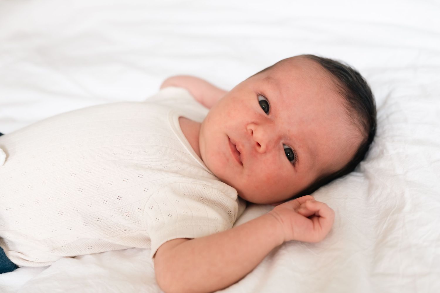 Serene close-up portraits on white bedding showing peaceful expressions.