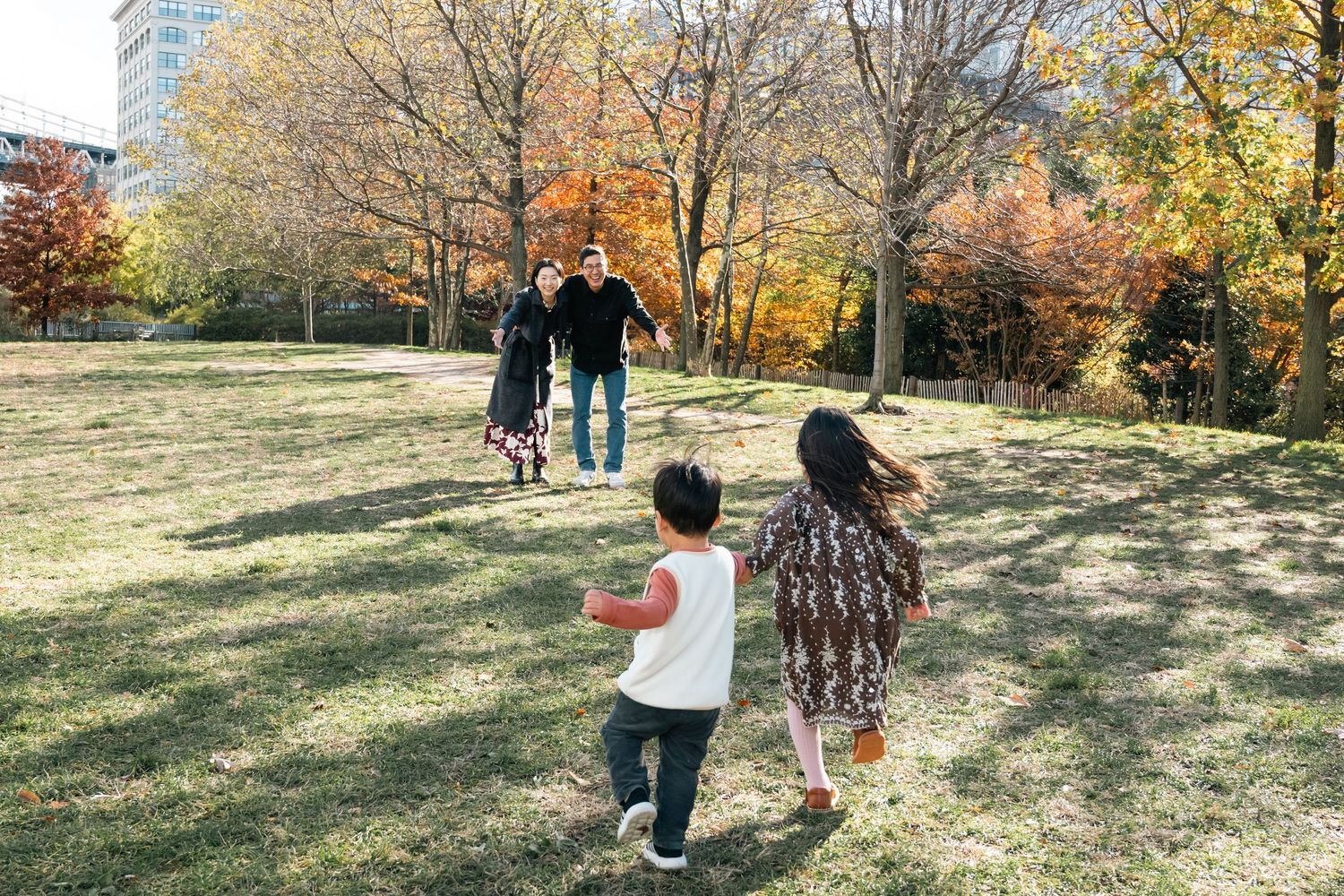 A group walks together through a sunny autumn park with golden leaves scattered on the ground.