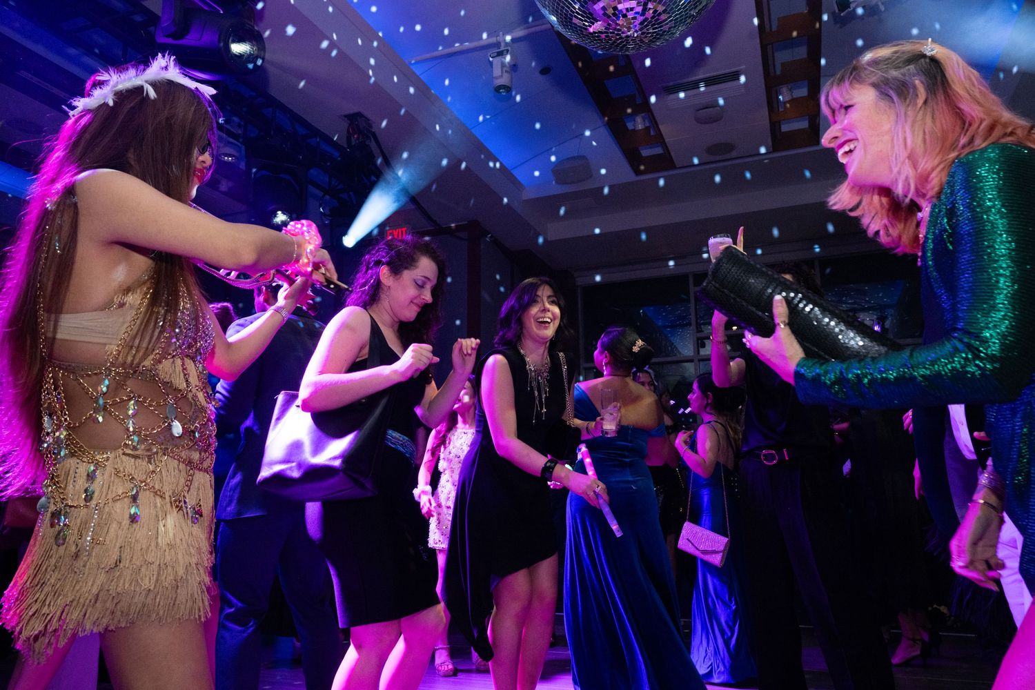 Guests in formal attire dancing energetically on a colorful illuminated dance floor at a gala.