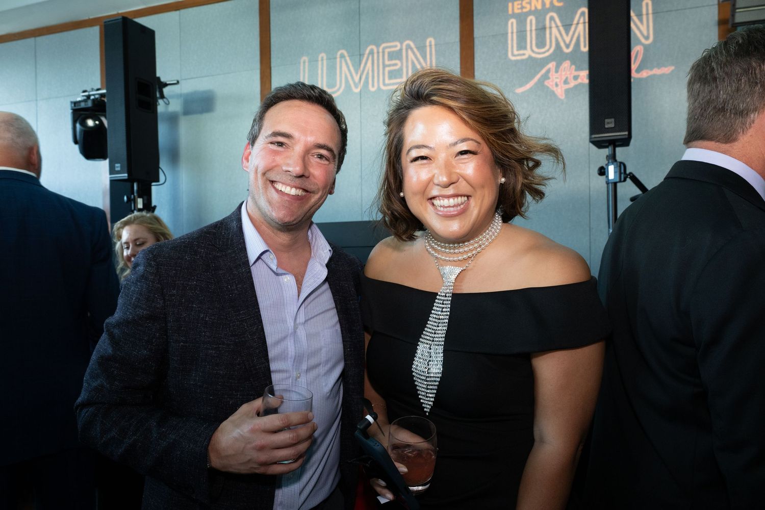 Two guests smiling at a formal evening event with Lumen signage in the background.