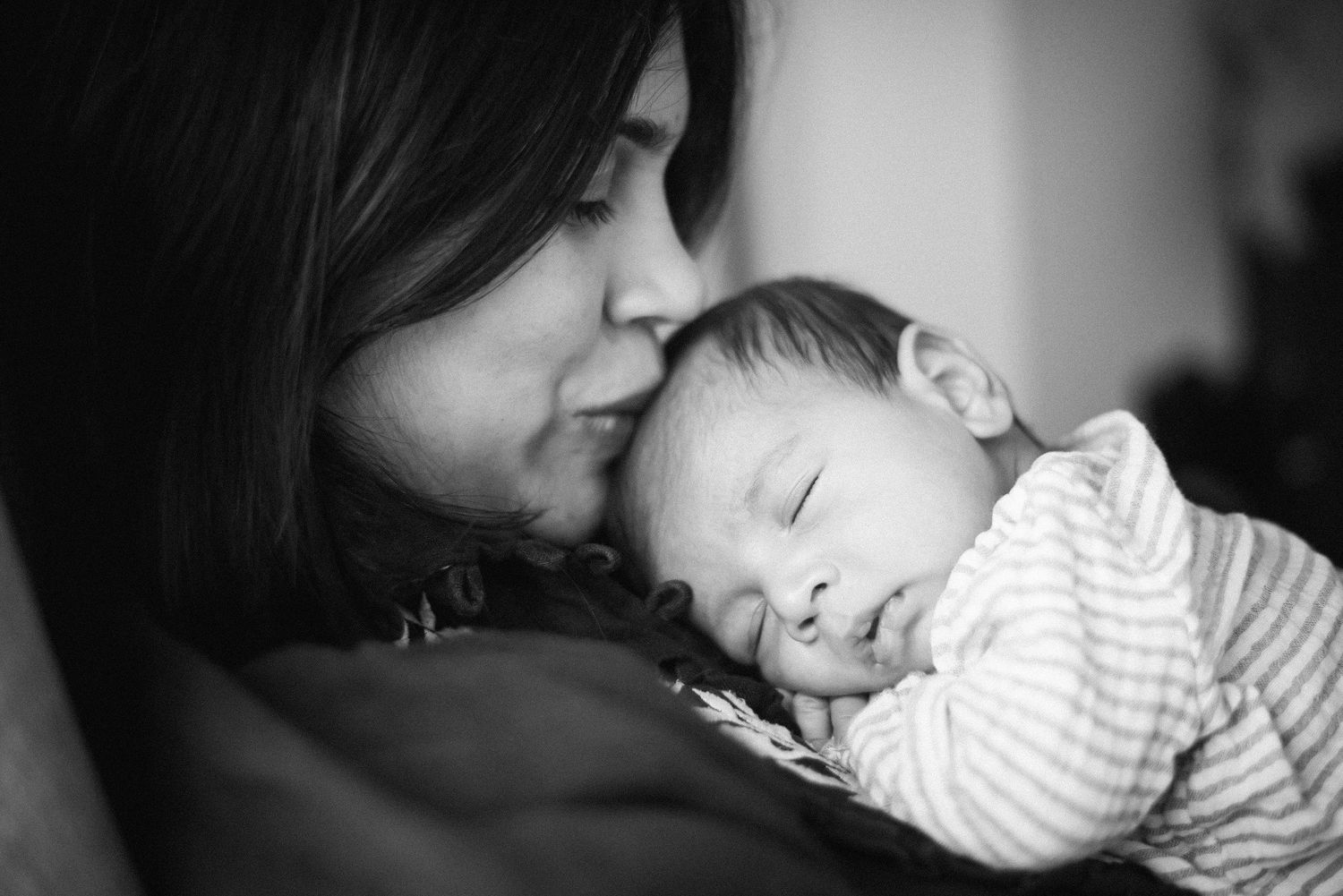 Black and white photo series showing tender moments between parent and infant in intimate lighting.