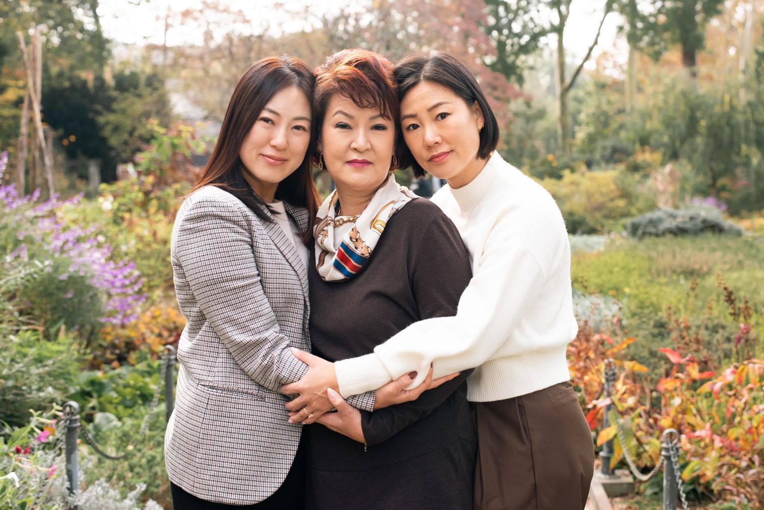 Three people share an intimate embrace while taking photos outdoors in autumn.