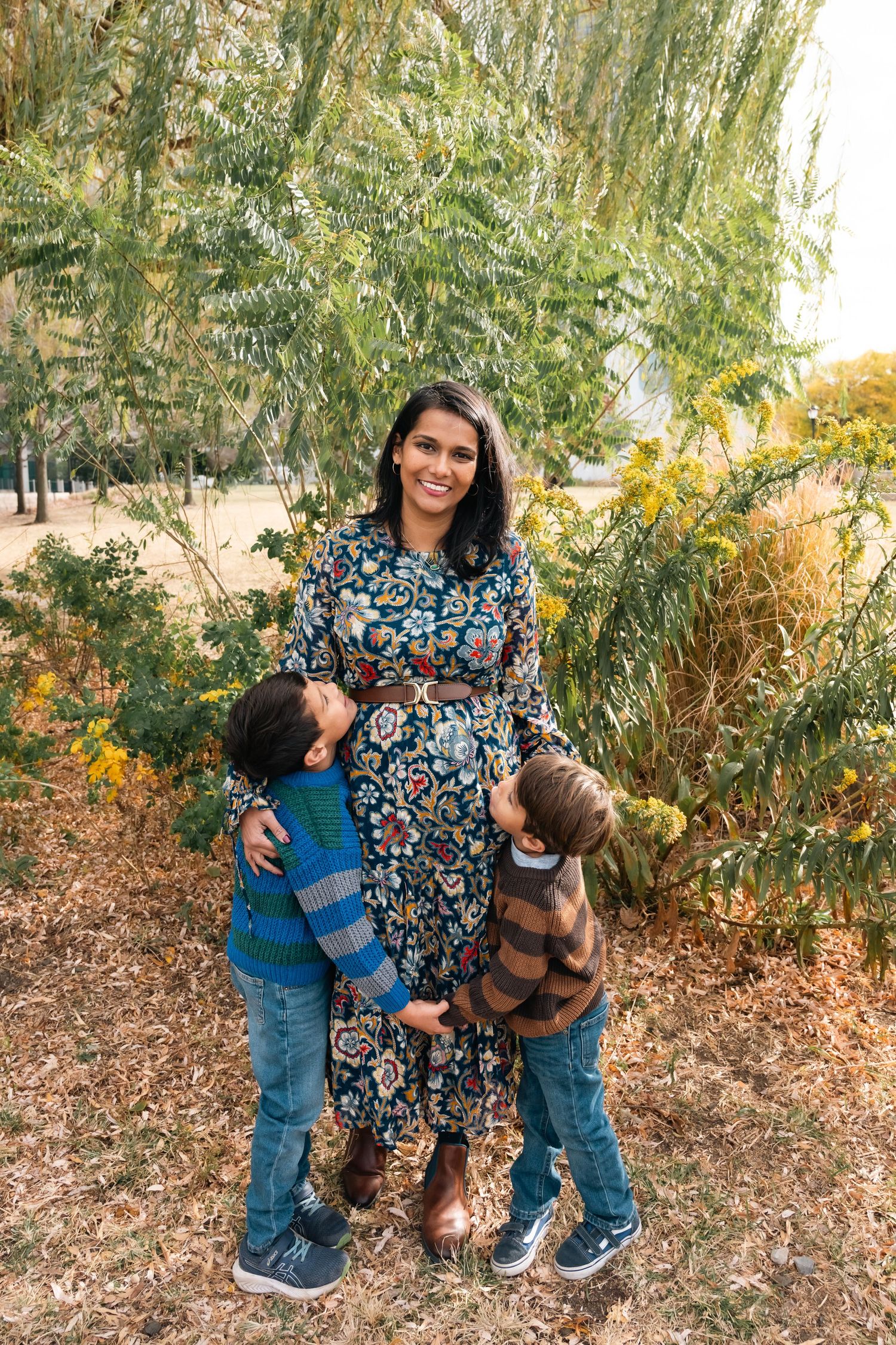 Autumn family photoshoot with colorful foliage and flowers in an outdoor setting.