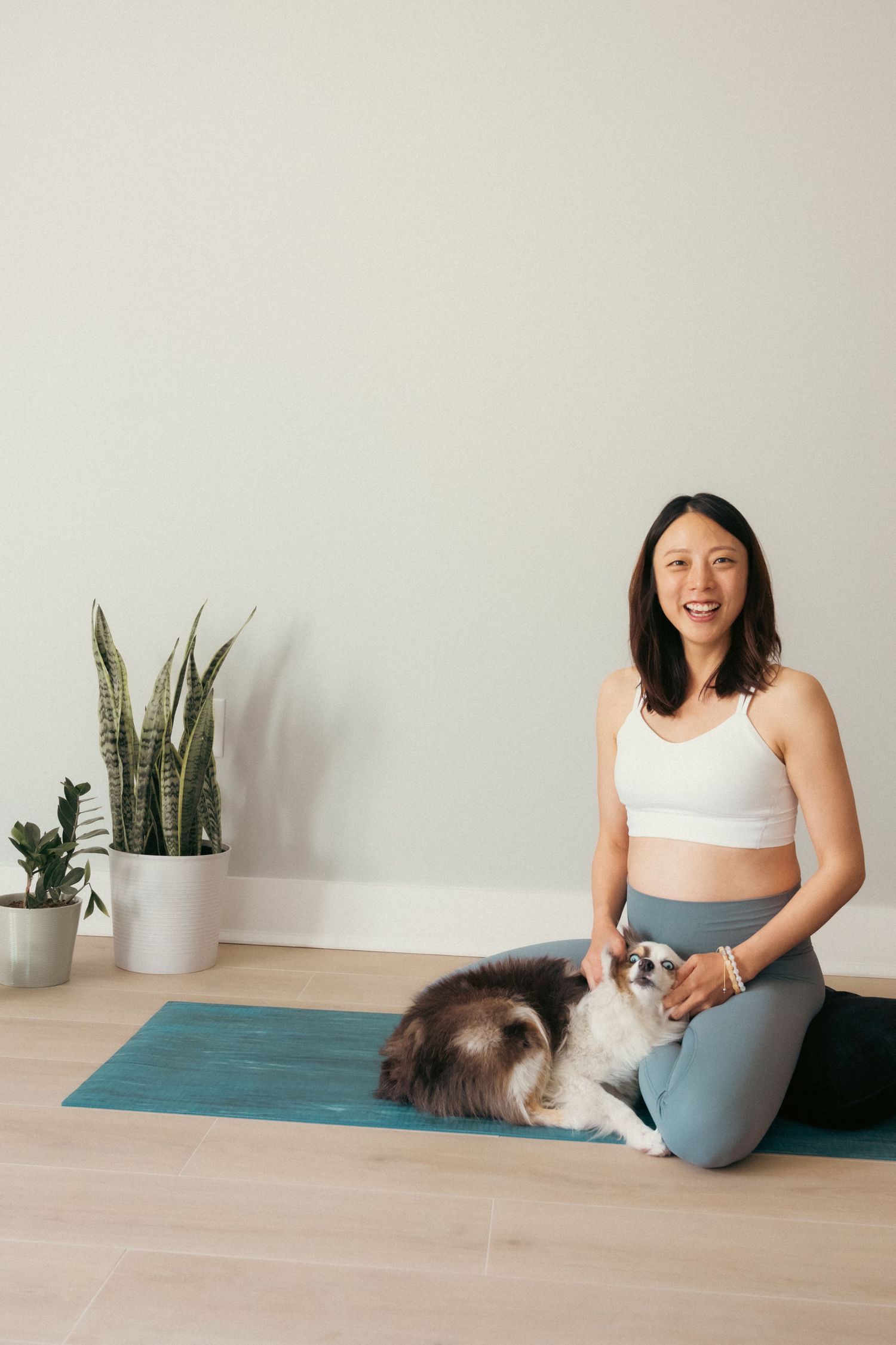 Playful interaction between a person and cat during yoga practice on a blue exercise mat.