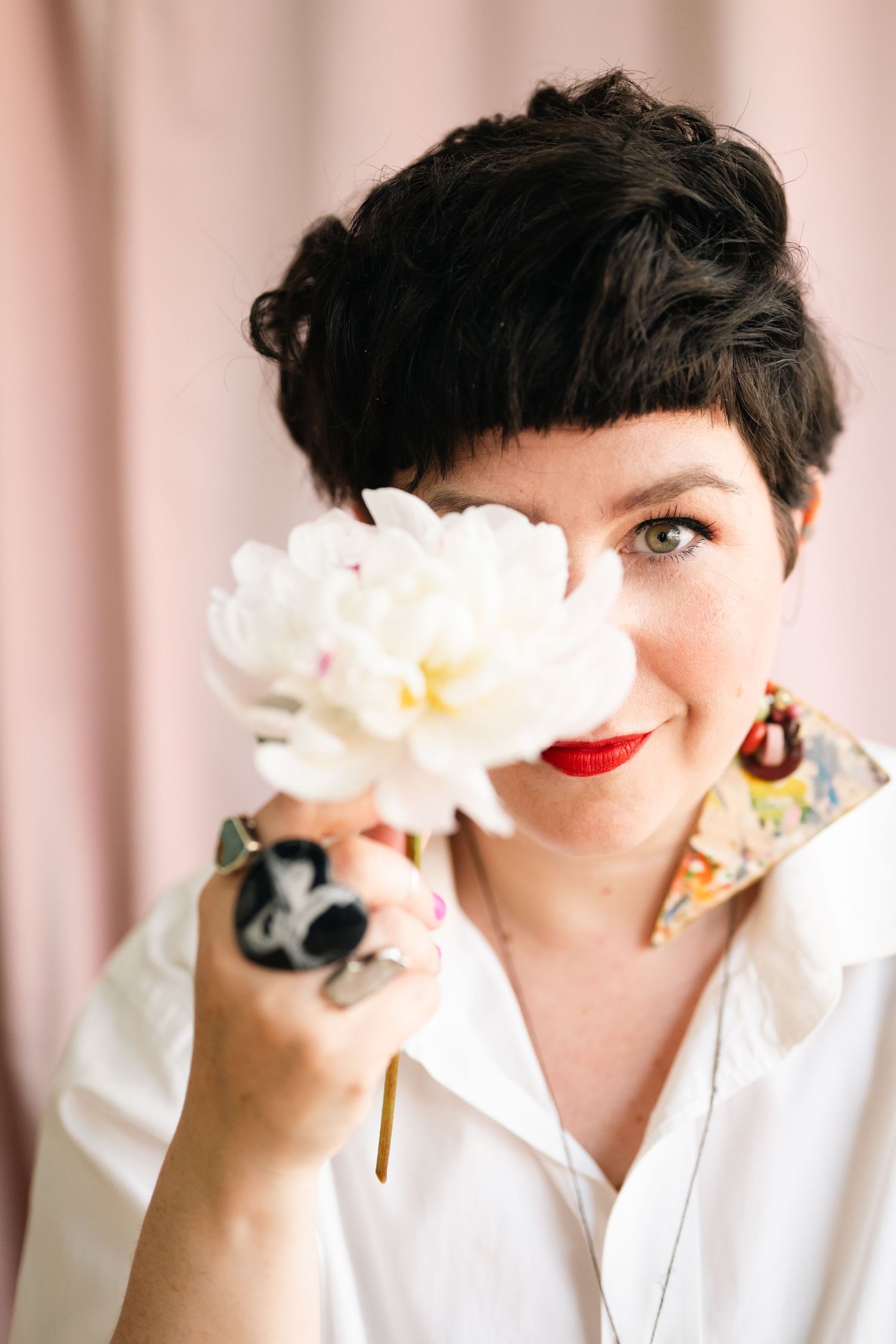 Creative portrait series featuring white flowers held up against pink background.