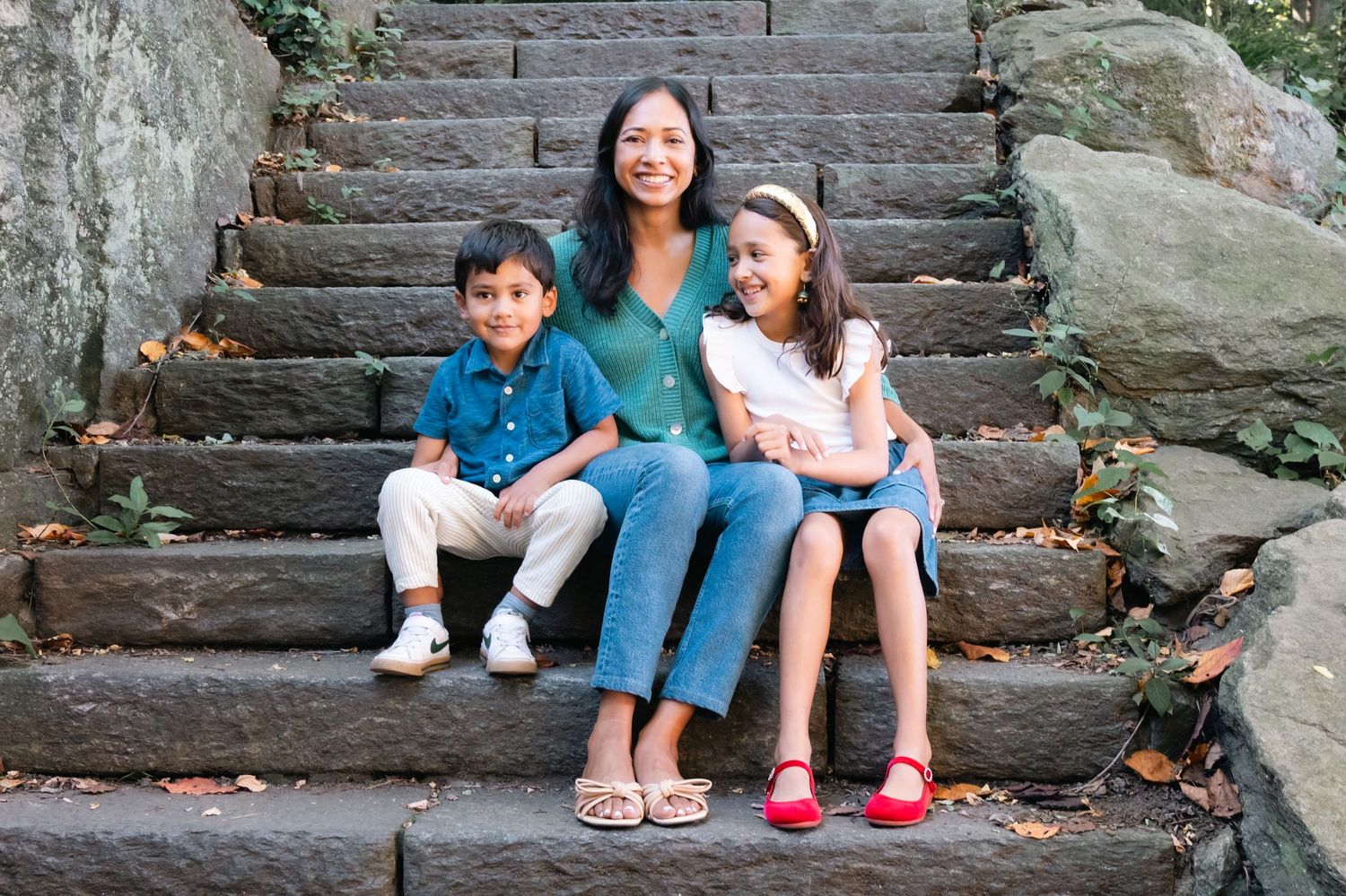 People sitting on stone steps outdoors in casual clothing enjoying a sunny day together.