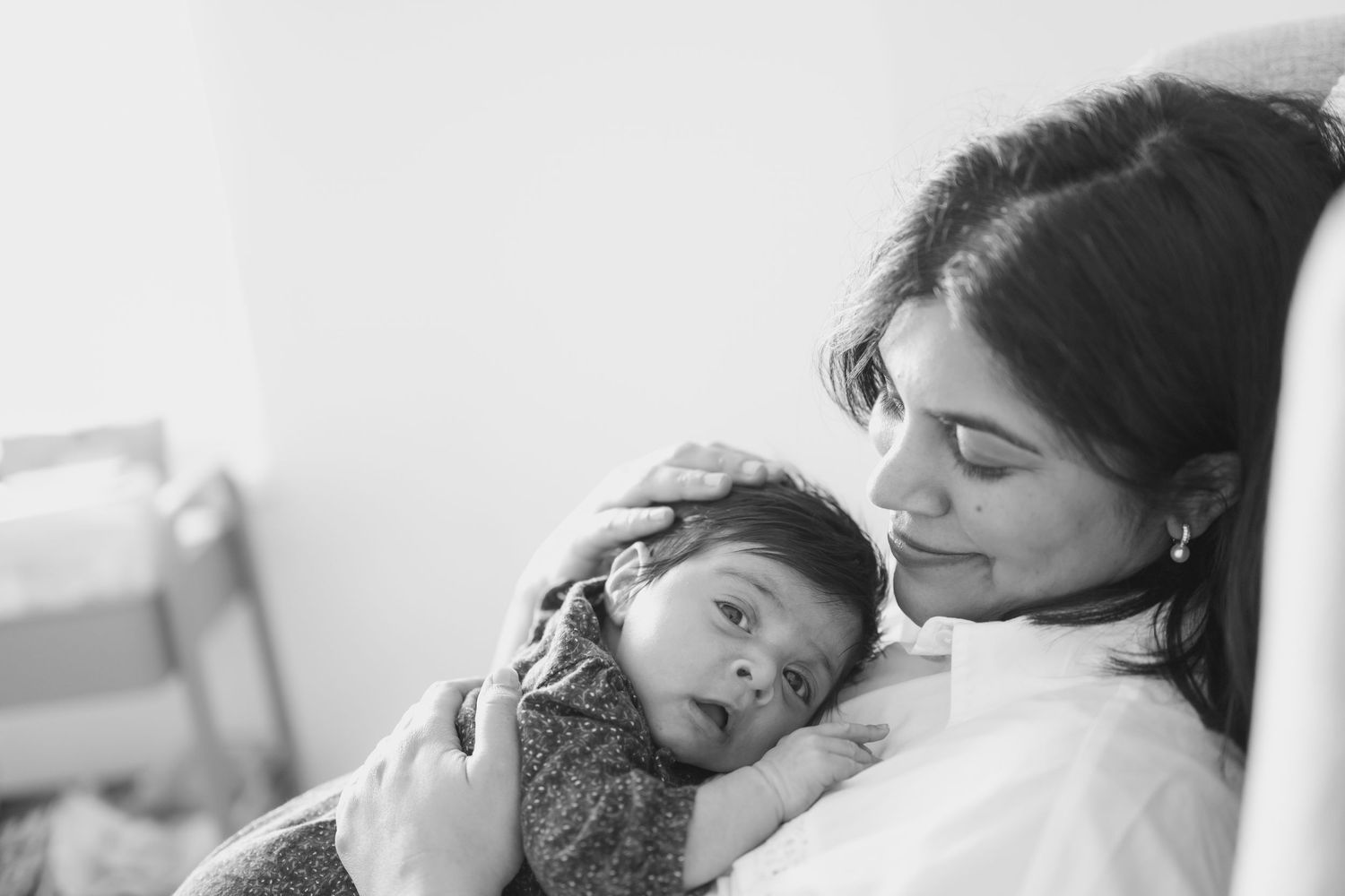 Black and white photo of a mother tenderly cradling her newborn baby, sharing a peaceful bonding moment.