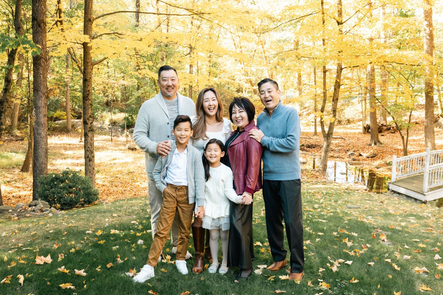 Family enjoying a golden autumn afternoon in a park with fallen leaves.