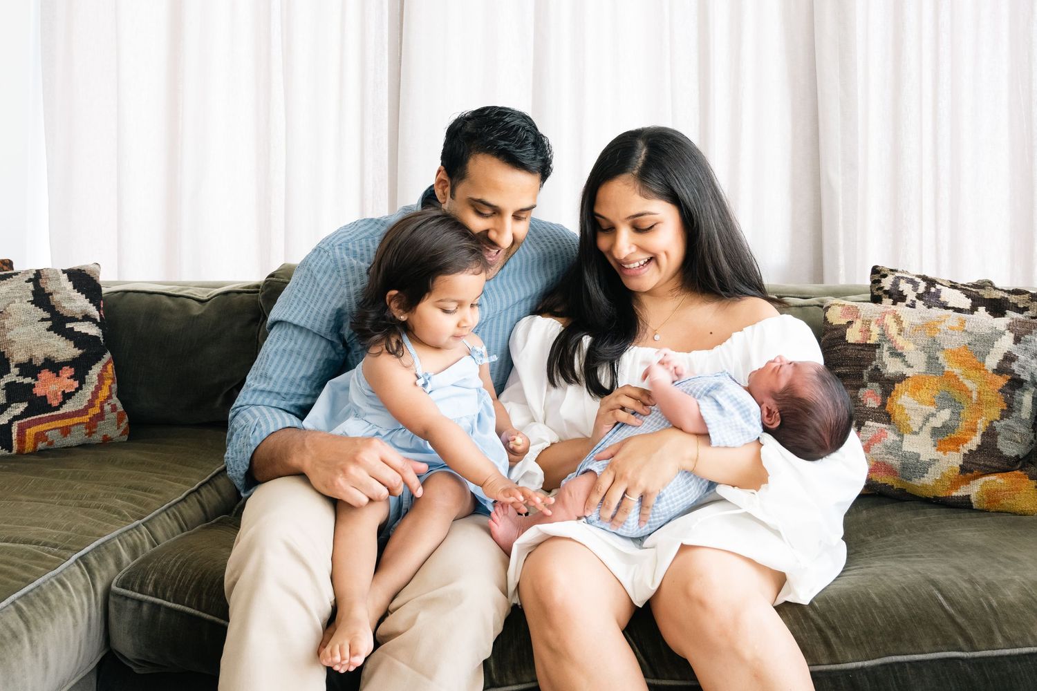 Family sharing tender moments together on gray couch with cushions.