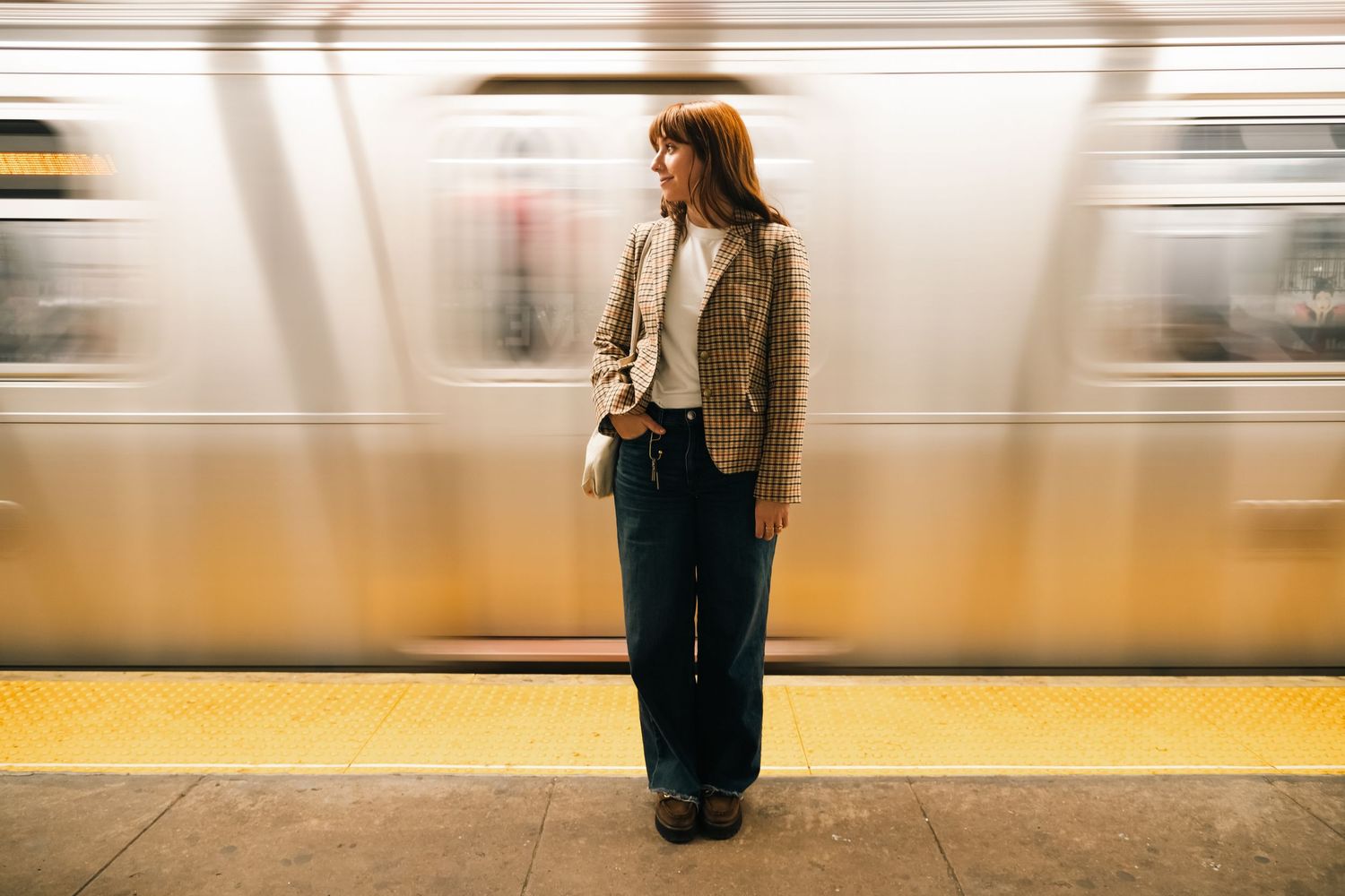 Motion-blurred subway platform scene with figure standing against moving train.
