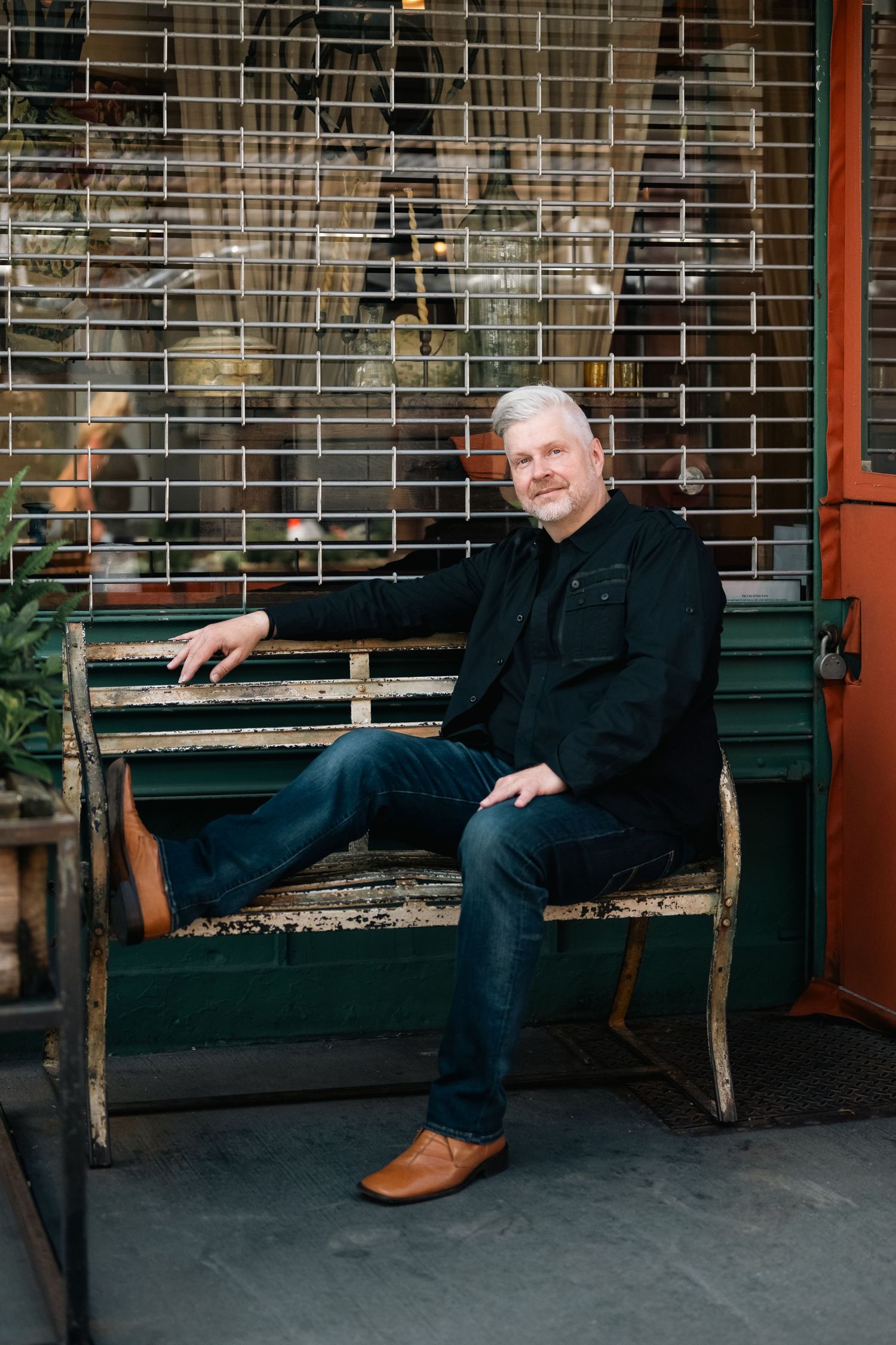 Casual poses on wooden bench outside storefront showing relaxed demeanor.