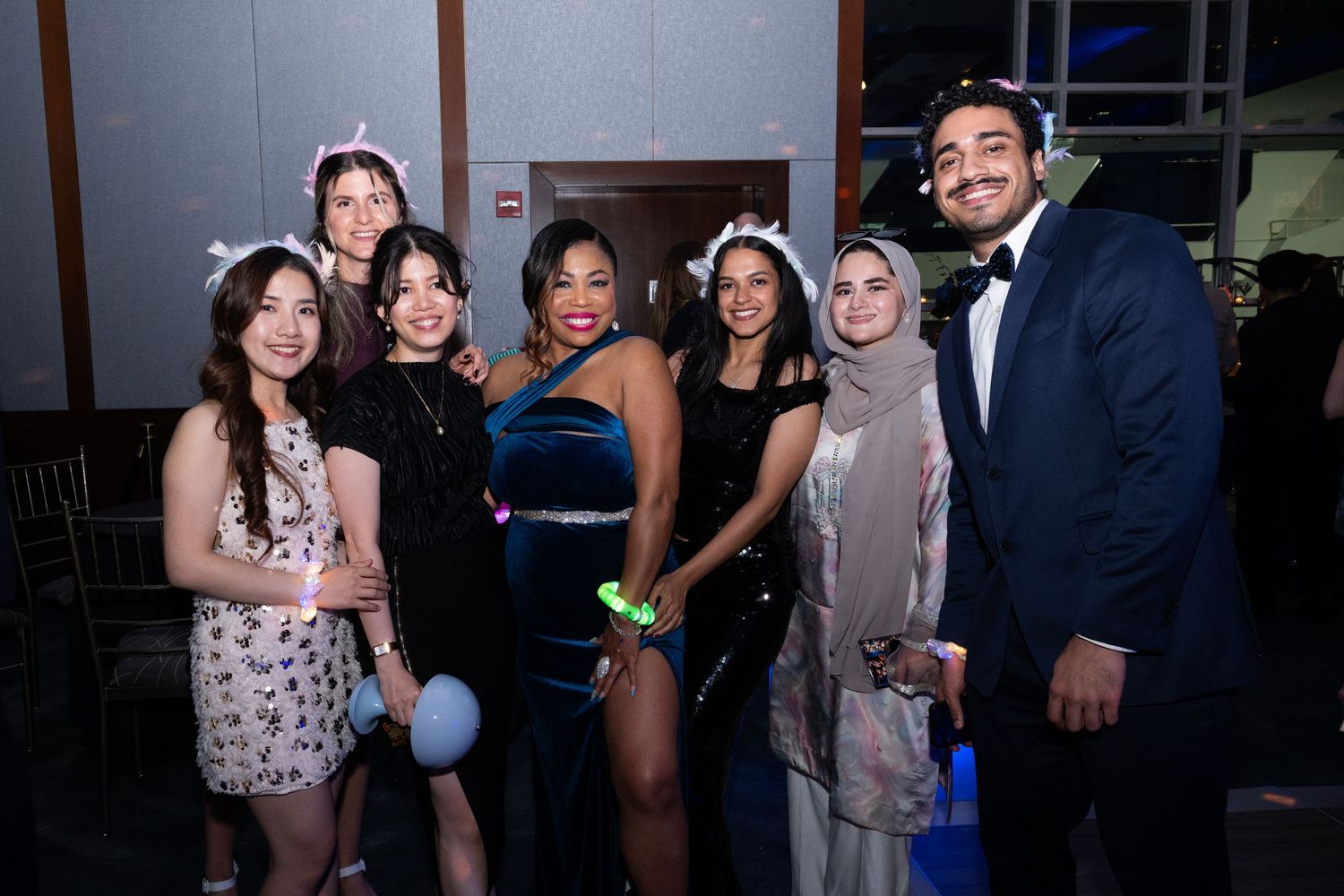 Group of seven friends posing together at a formal gala event, dressed in elegant attire.