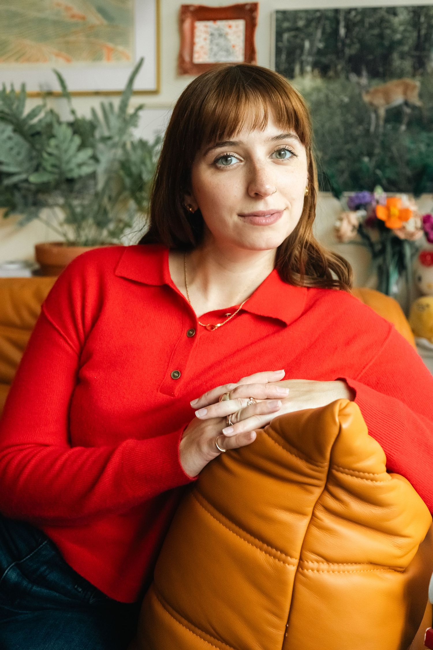 Casual indoor portrait series with person in red sweater hugging an orange cushion.