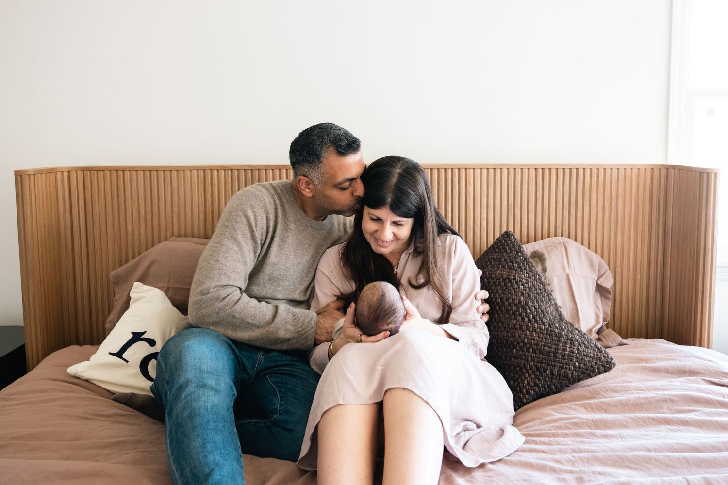 Lifestyle family photography session with newborn baby on comfortable bed.