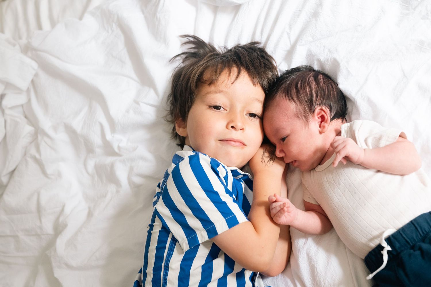 Sweet candid moments of family bonding and rest on white bedding.