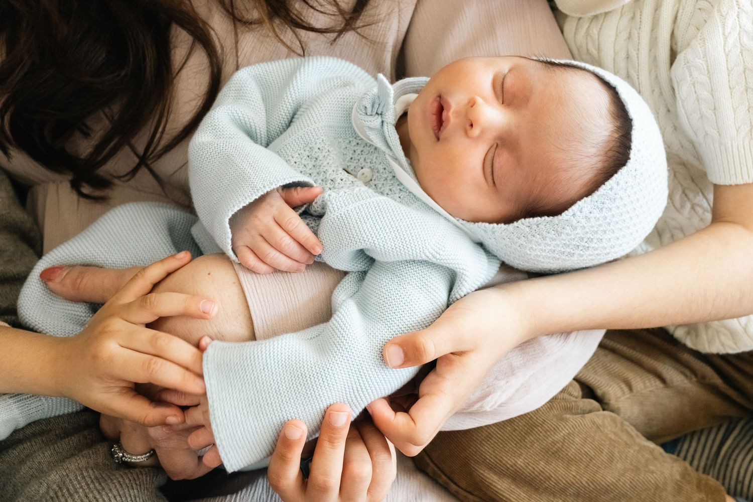 Close-up shots of tender family moments with newborn baby wrapped in light blue blanket.