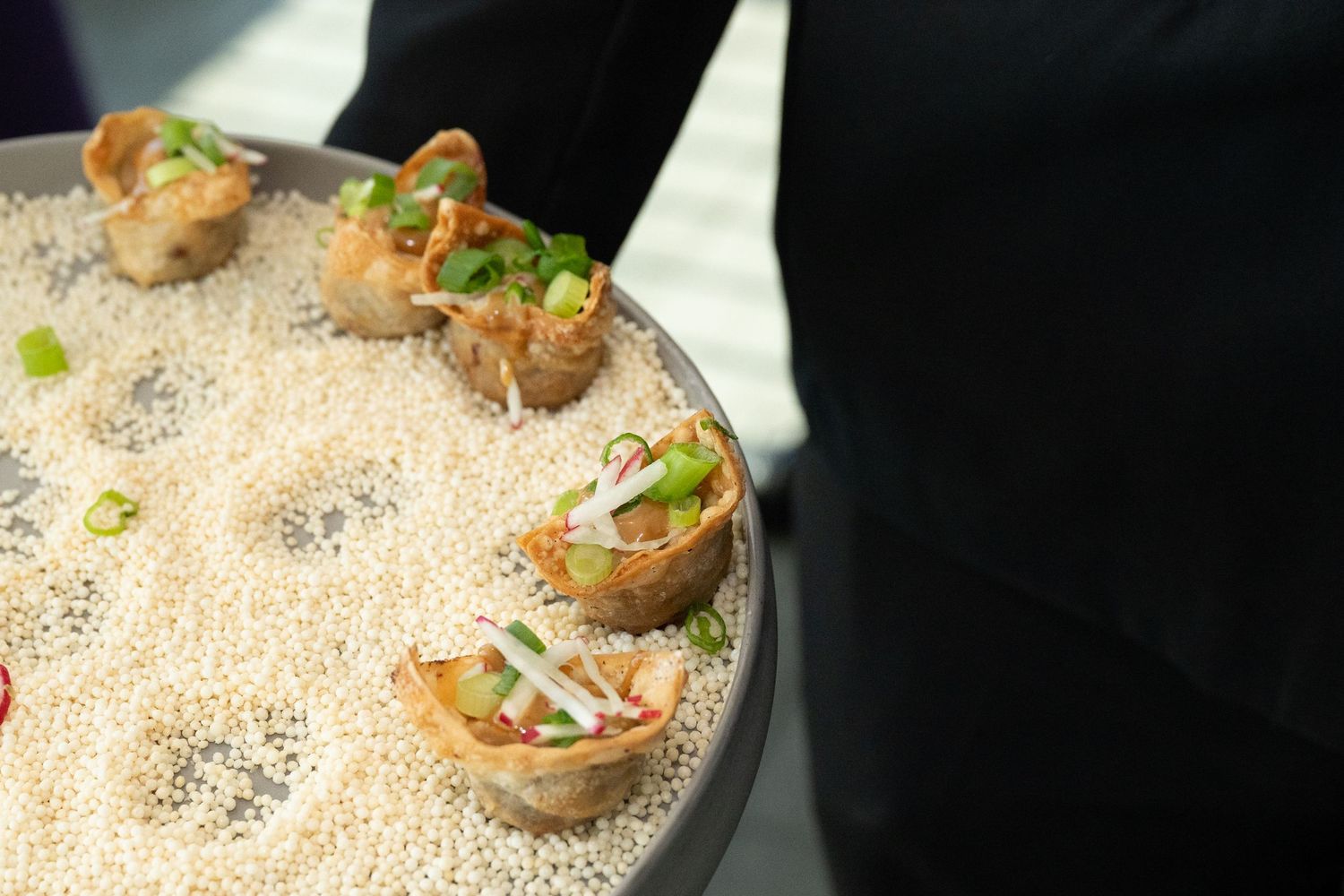 Elegant appetizers served in crispy wonton cups on a sesame seed tray, garnished with fresh vegetables.