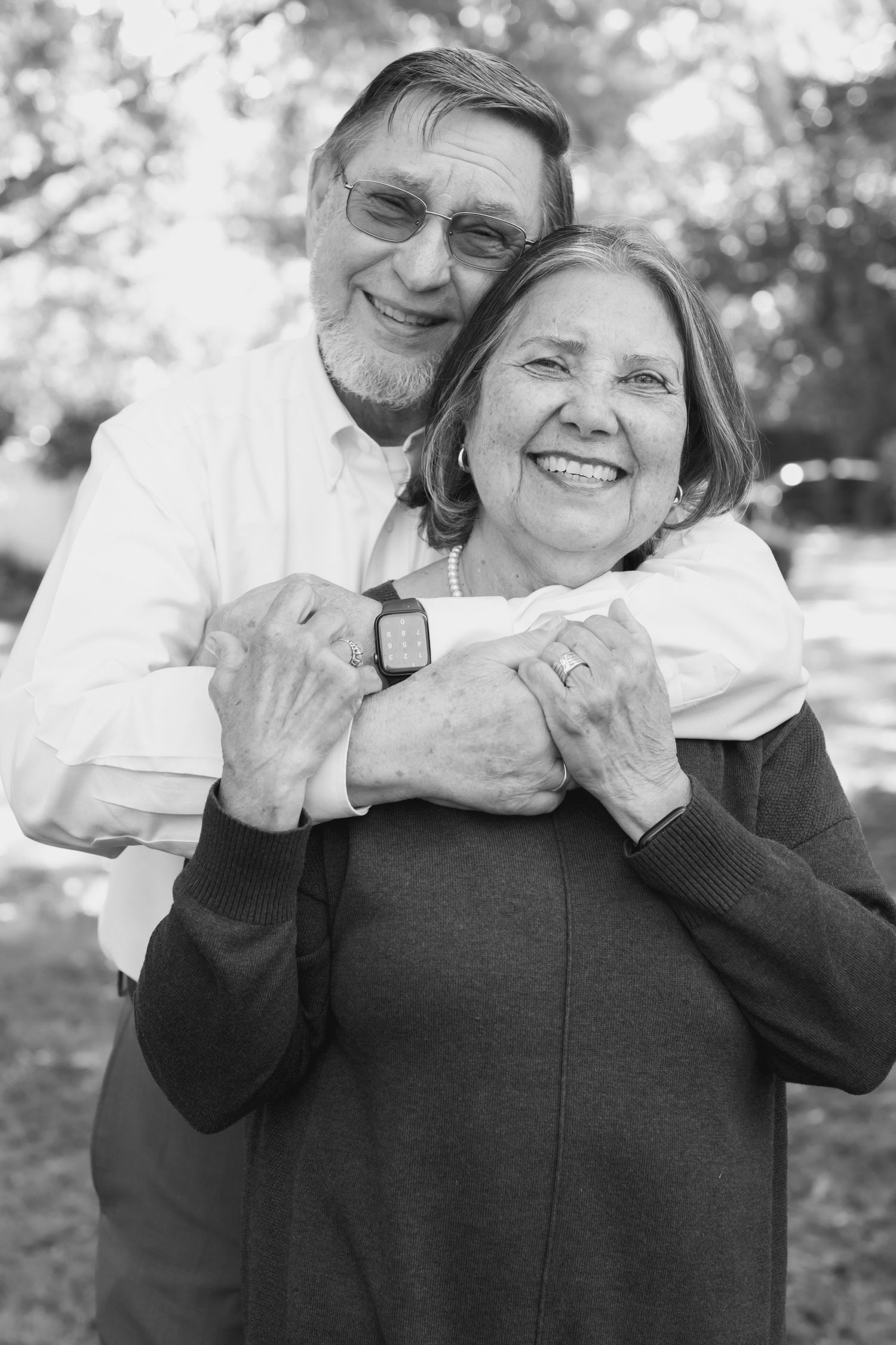 Black and white portrait of couple embracing and laughing together outdoors.
