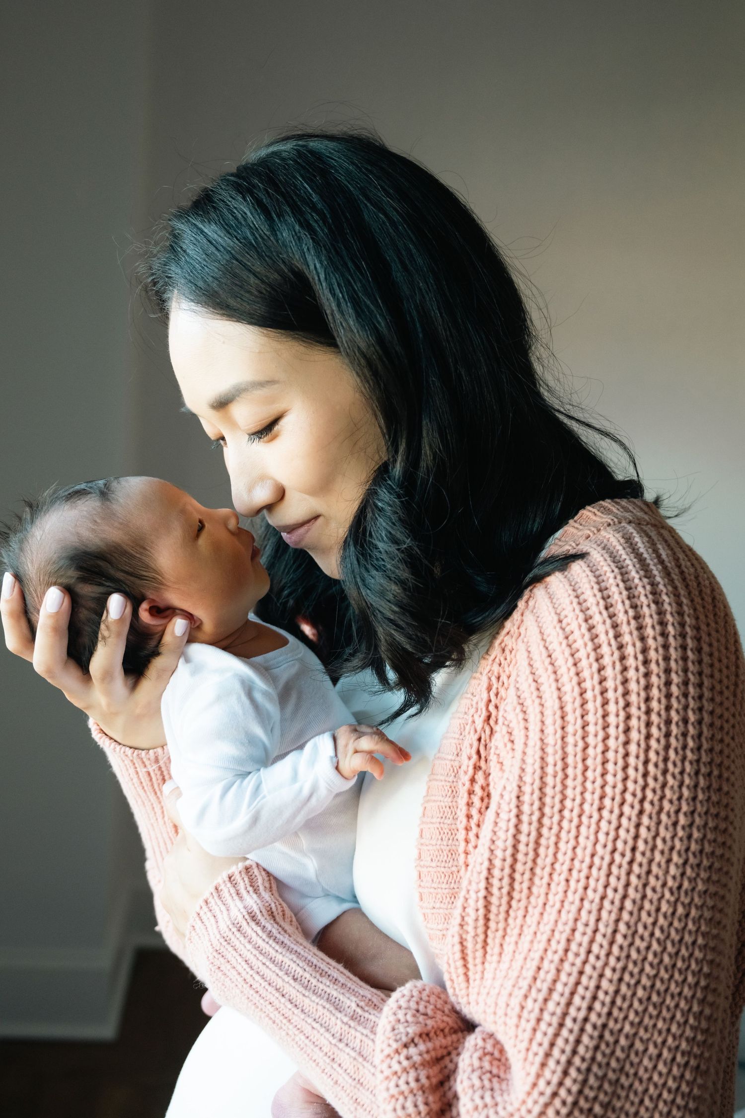 Intimate mother and baby portraits in soft natural window light.