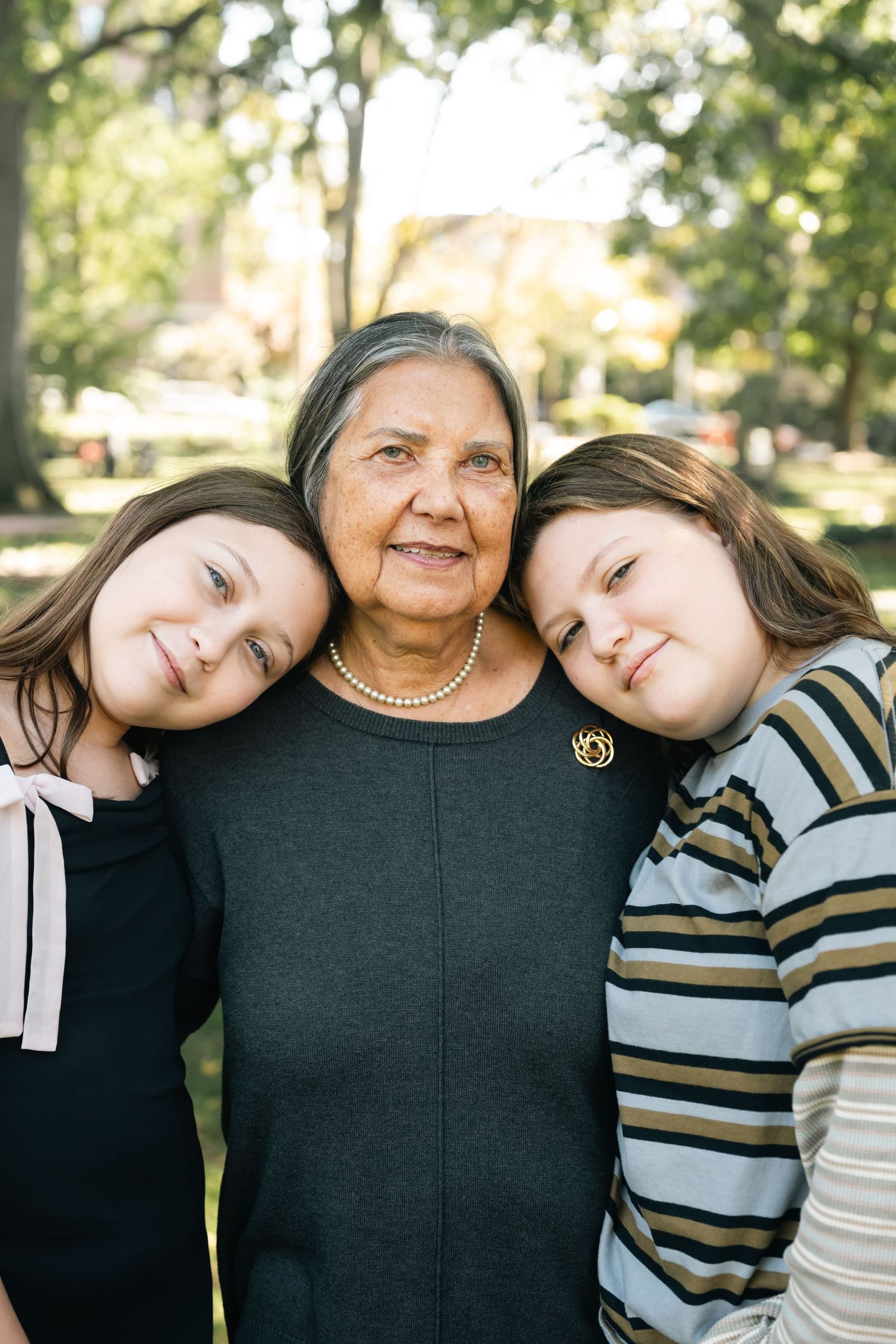 Three people sharing an affectionate moment while leaning in together outdoors.