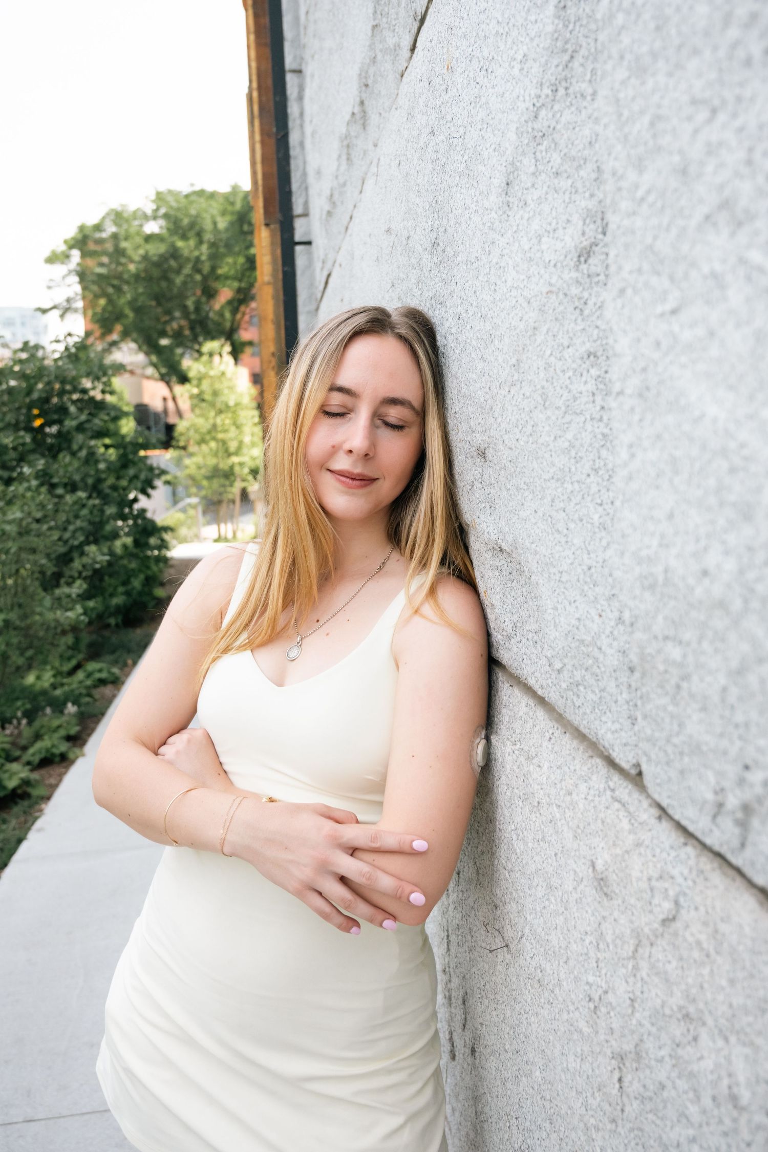 Woman in white dress posing against a textured wall during an outdoor yoga  photoshoot.