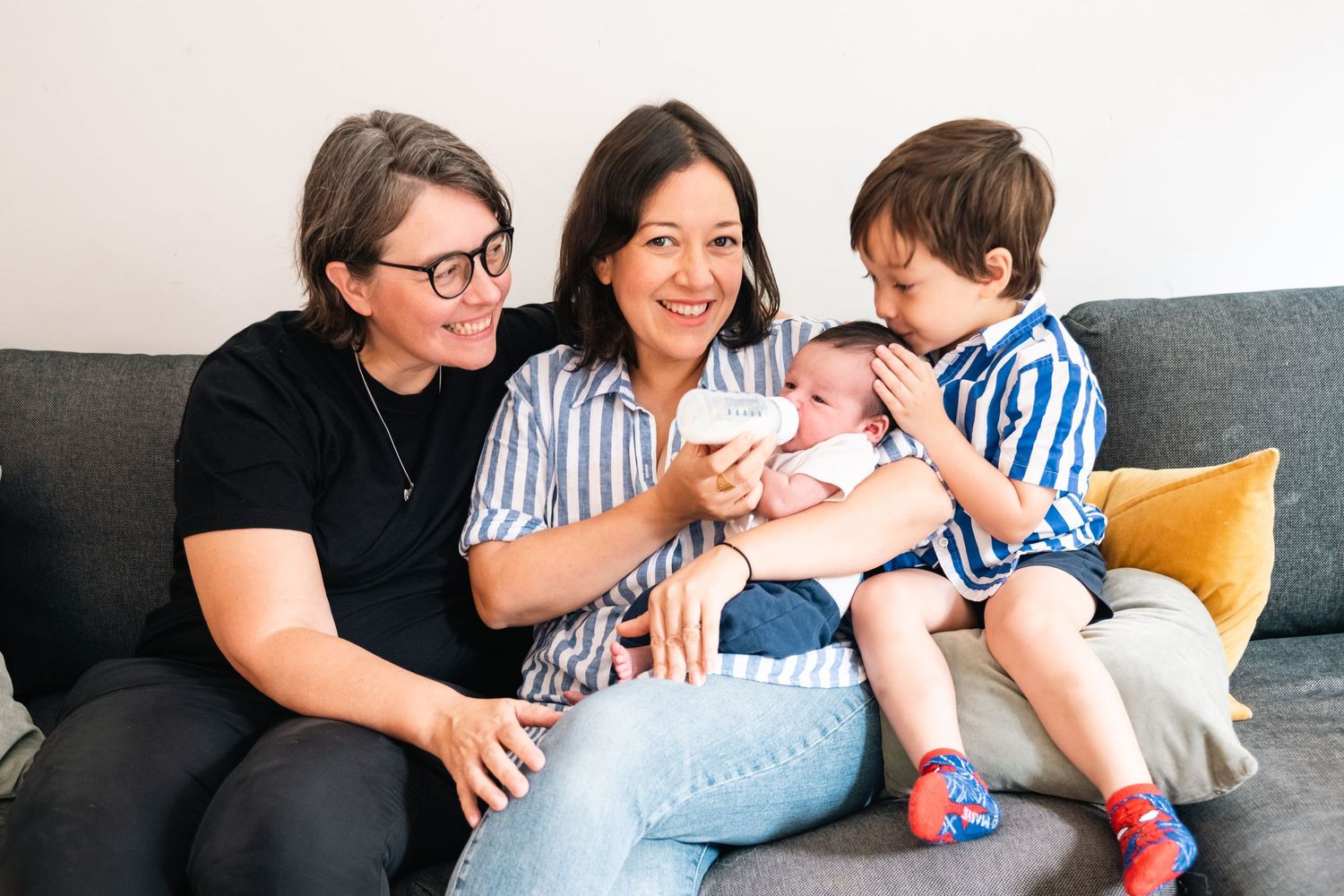 Family relaxing together on white couch during casual indoor photo session.