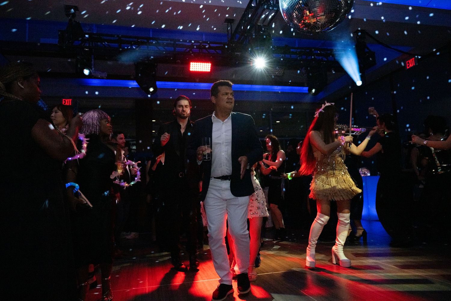 Guests dance energetically on a colorfully lit dance floor at a lively gala after-party.