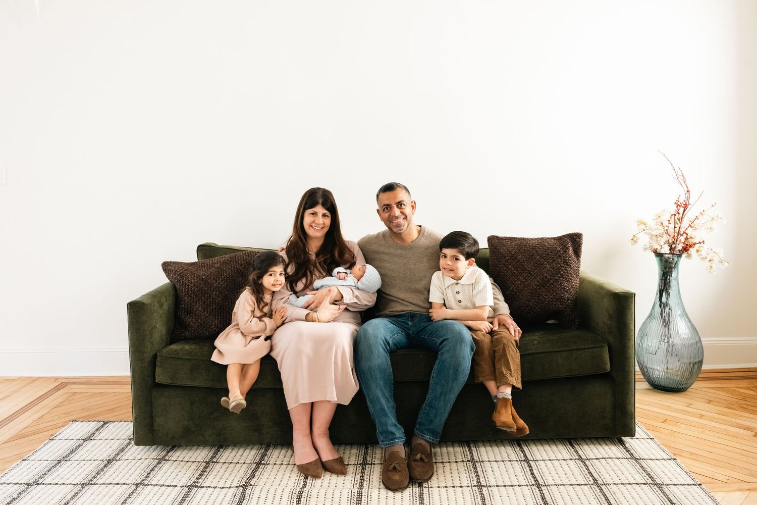 Lifestyle family photos showing relaxed moments on a grey couch in a minimalist white room.