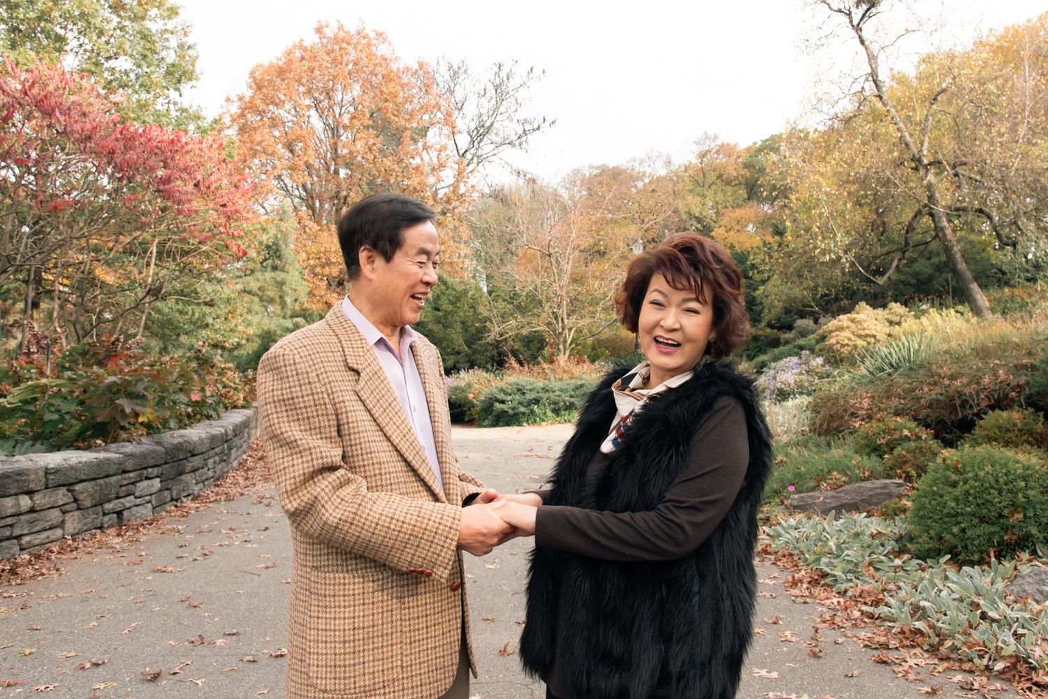 A couple enjoying a playful moment together on an autumn path surrounded by colorful fall foliage.