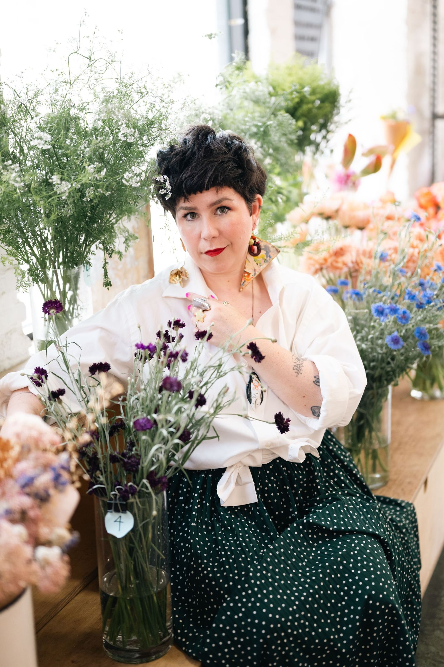 Artistic shots of person arranging flowers in vases against colorful garden backdrop.