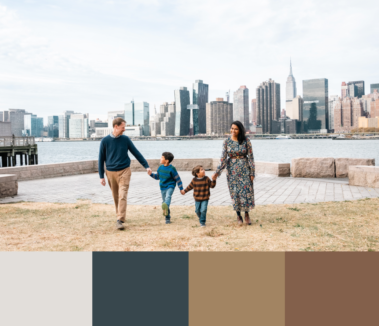 Family walking along waterfront with NYC skyline in background.