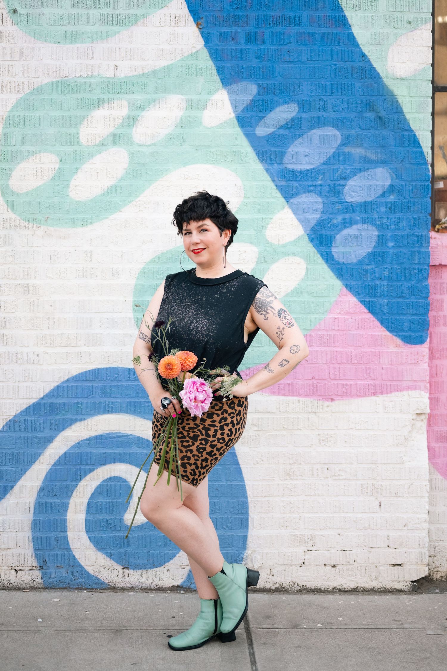 Playful poses against a colorful geometric mural featuring blue, mint and pink shapes.