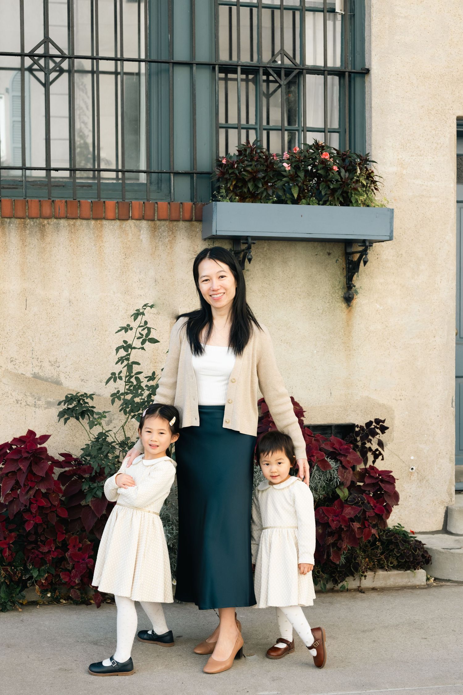 A sequence of family portraits against a building wall with red flowers and green railings.