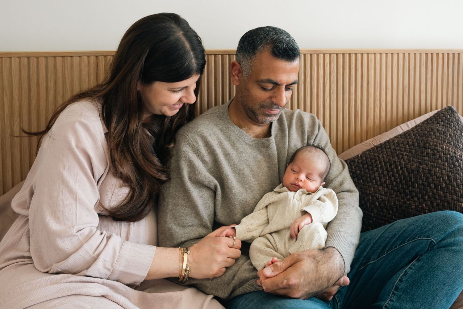 Family relaxing together on bed during intimate lifestyle newborn photography session.