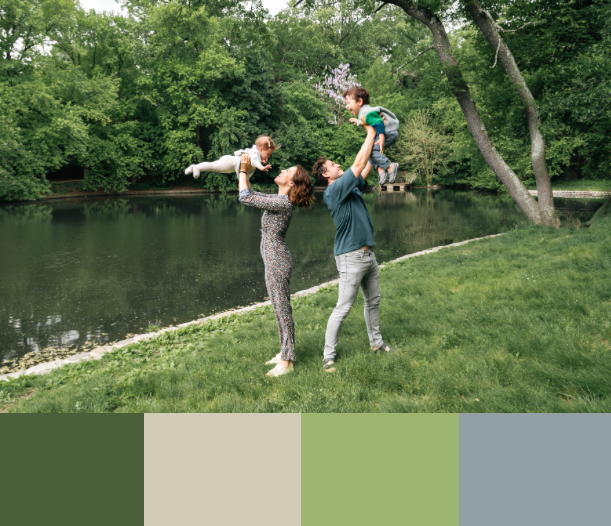 People enjoying a sunny day on a grassy hill near a pond in a lush park setting.